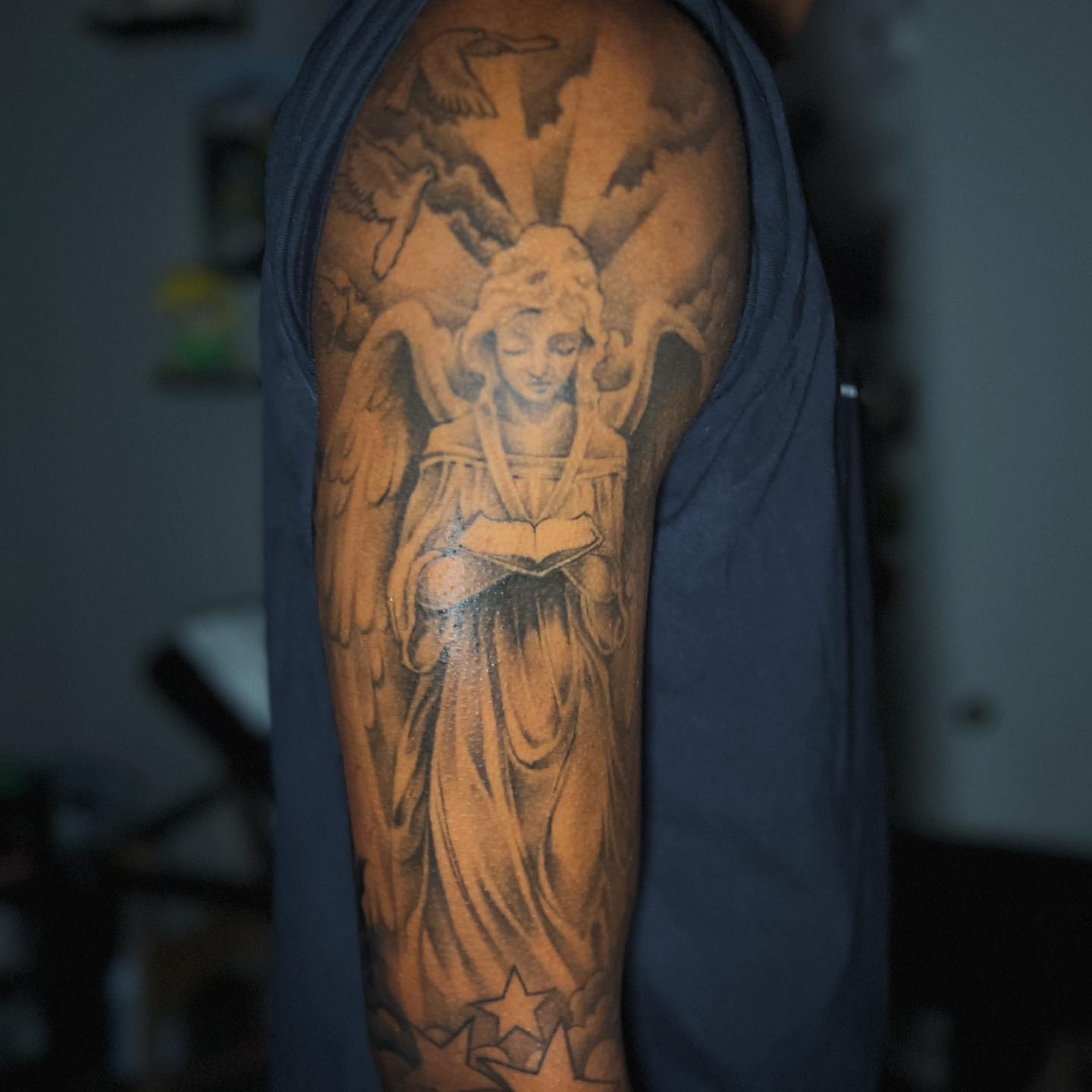 Angel reading book black and grey tattoo on the forearm by Matthew Arguello