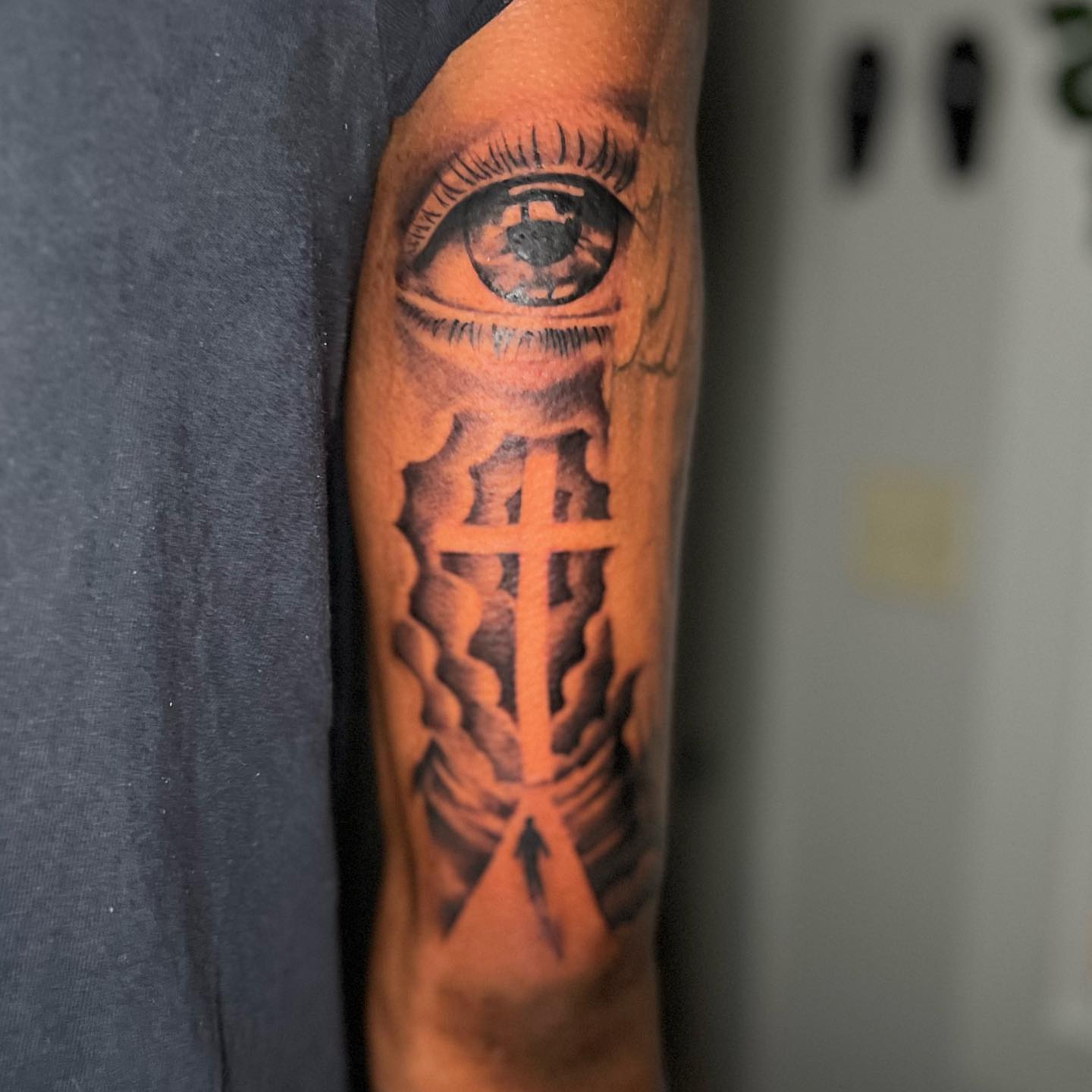 Eye and cross black and grey tattoo on the forearm by Matthew Arguello