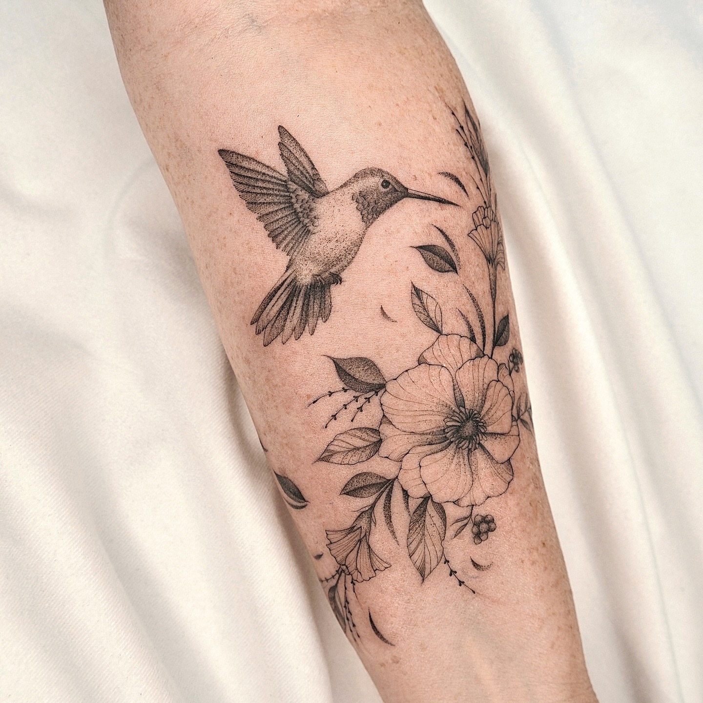 Hummingbird and flowers realism tattoo on the forearm by Houston Tattoo Artist