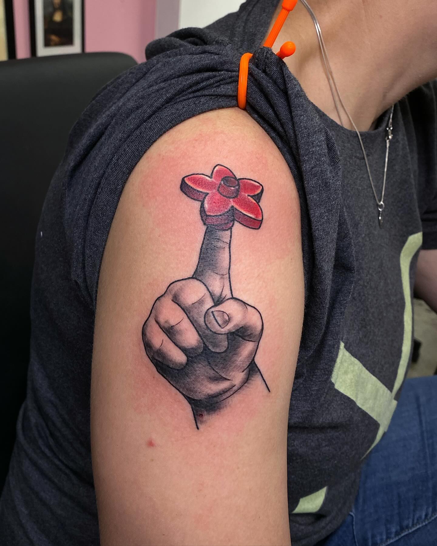 Middle finger with flower realism tattoo on the upper arm by @kaitlin.tattoos, Richmond, Virginia