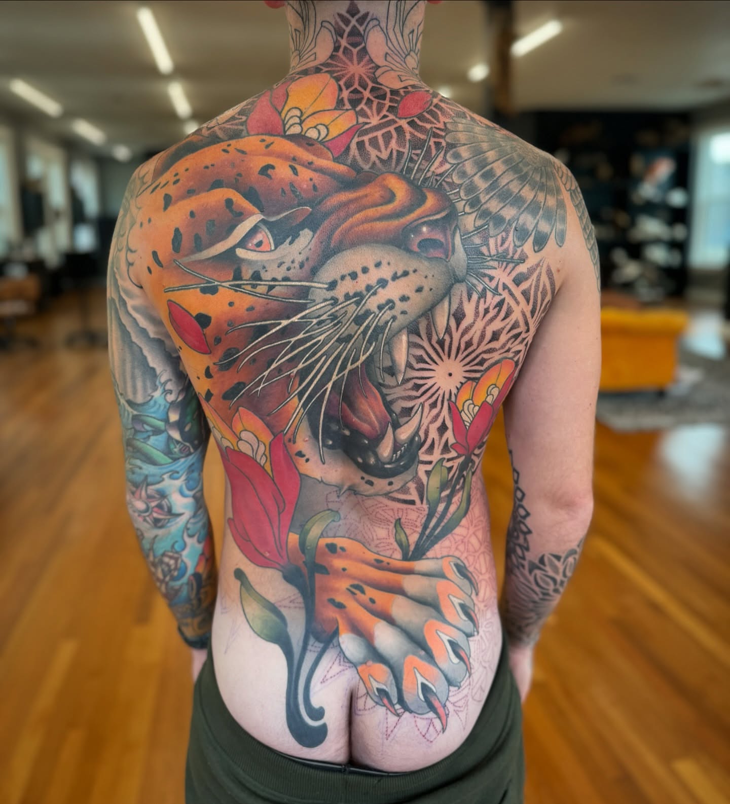 Jaguar and flowers realism tattoo on the back by Paul Schnell