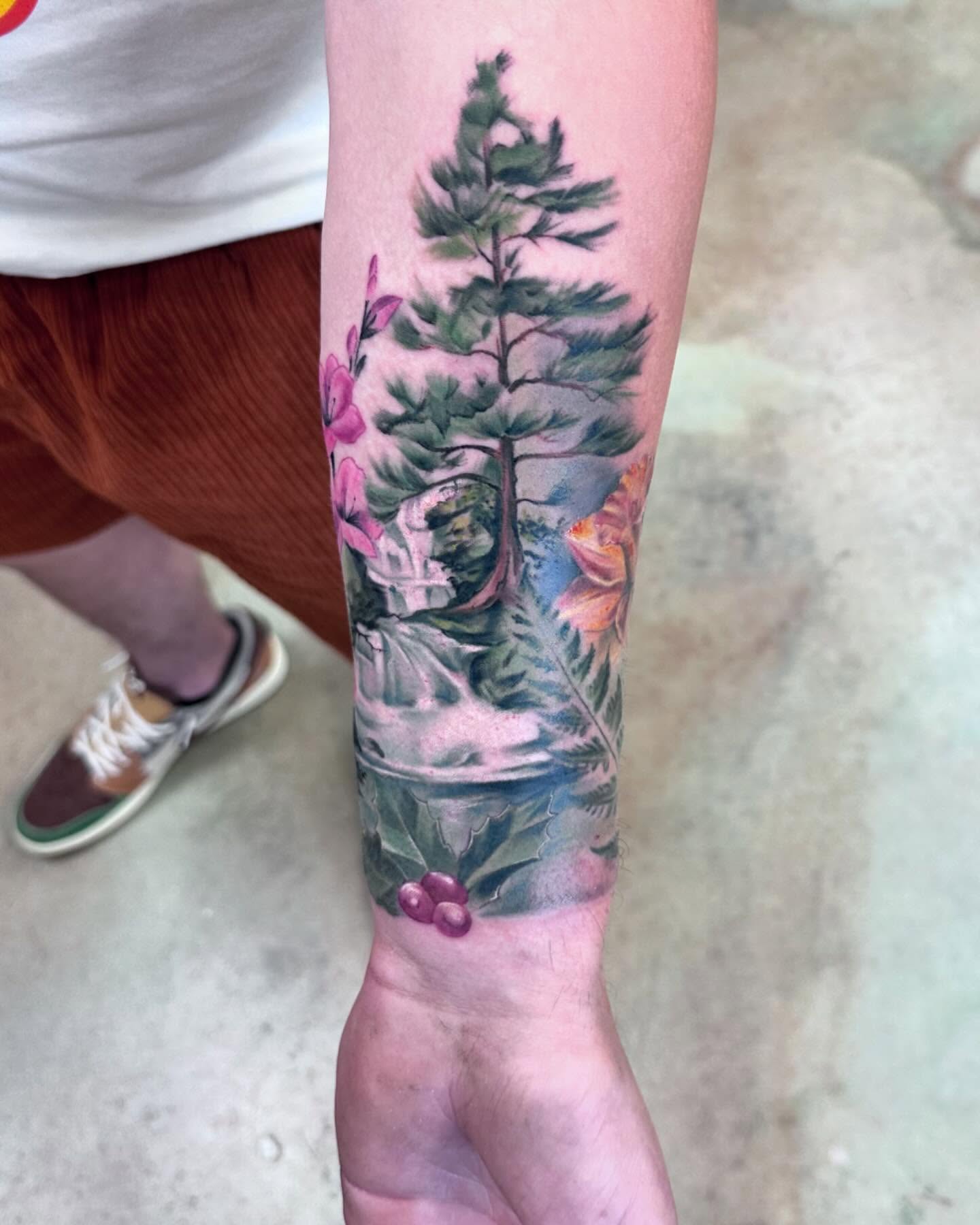 Pine tree and flowers realism tattoo on the forearm by Shawn Cook
