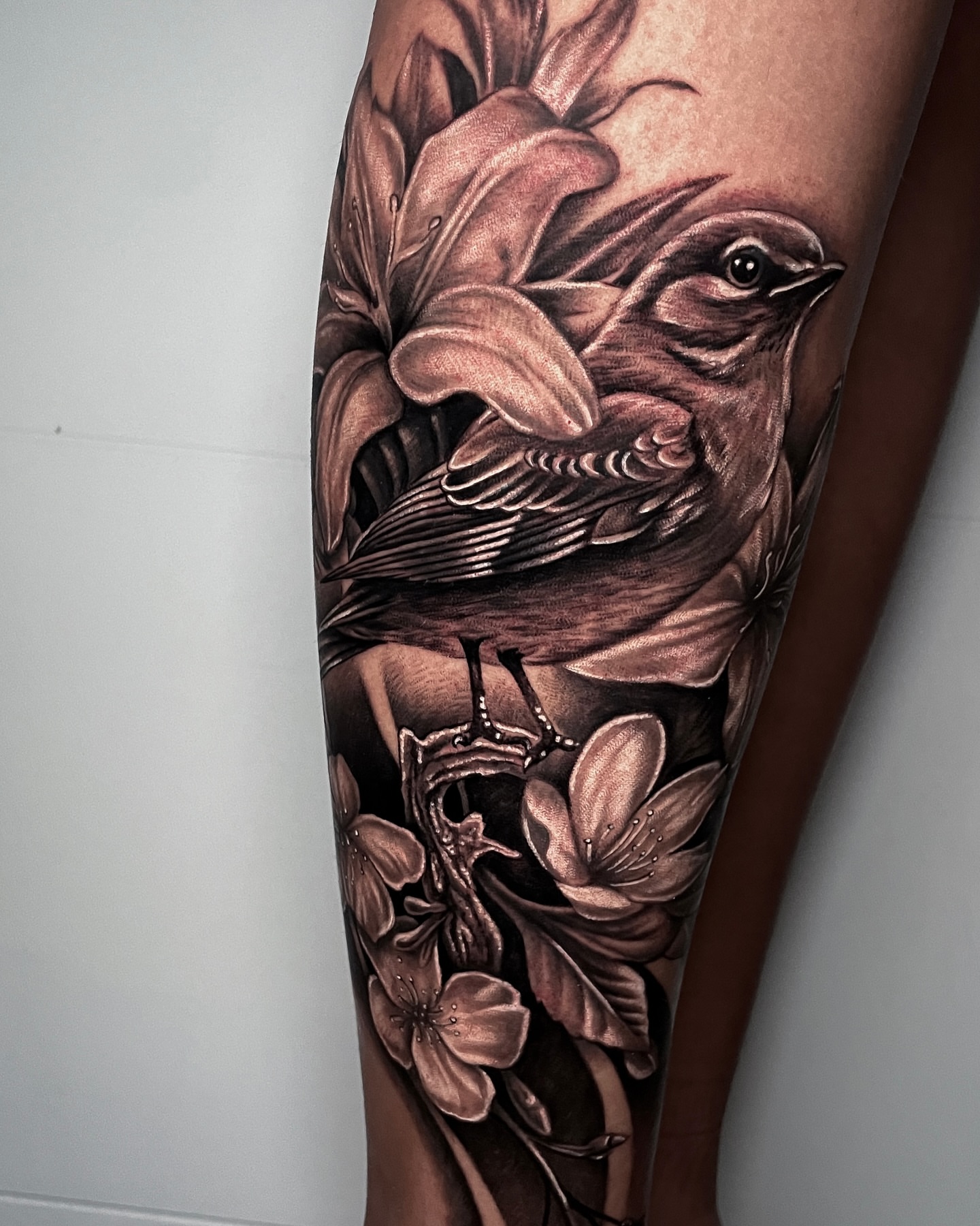 Bird and flowers realism tattoo on the forearm by Christian Pelaez