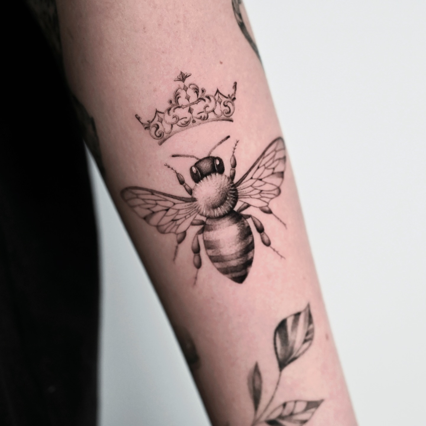 Bee with crown black and grey tattoo on the forearm by dom