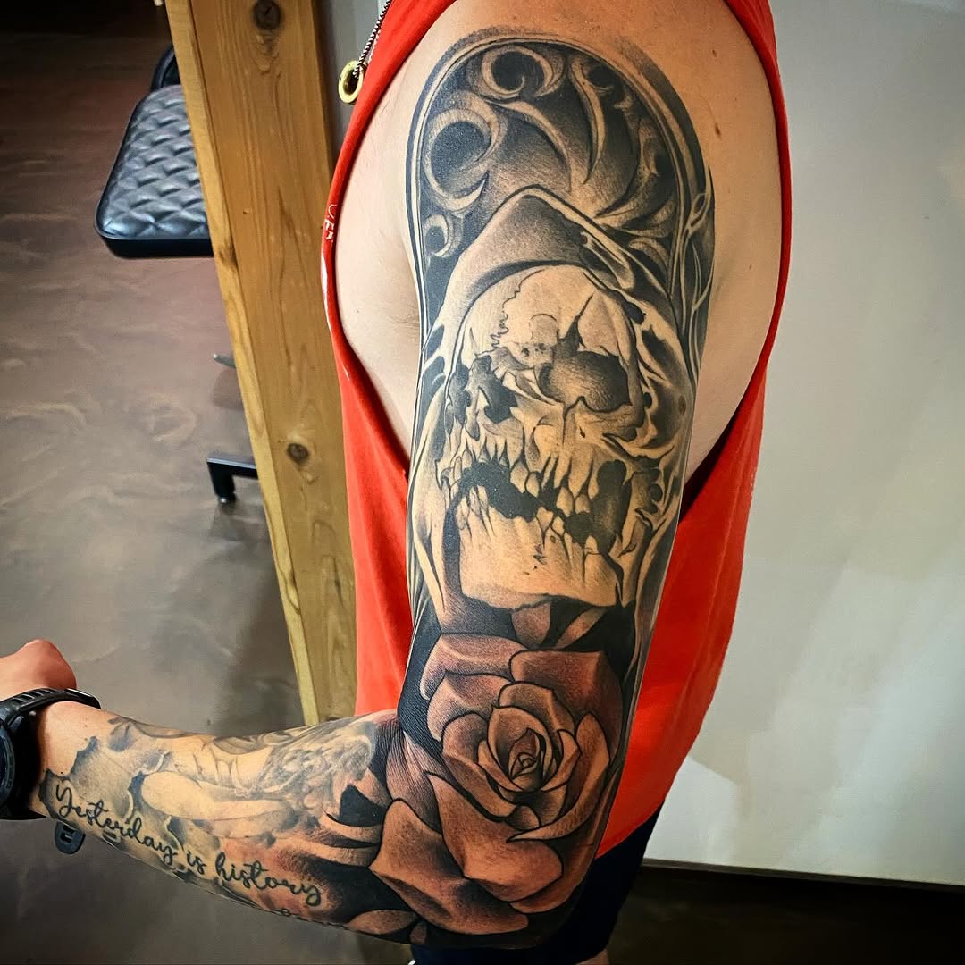 Skull and rose realism tattoo on the upper arm by Cody Wolfe