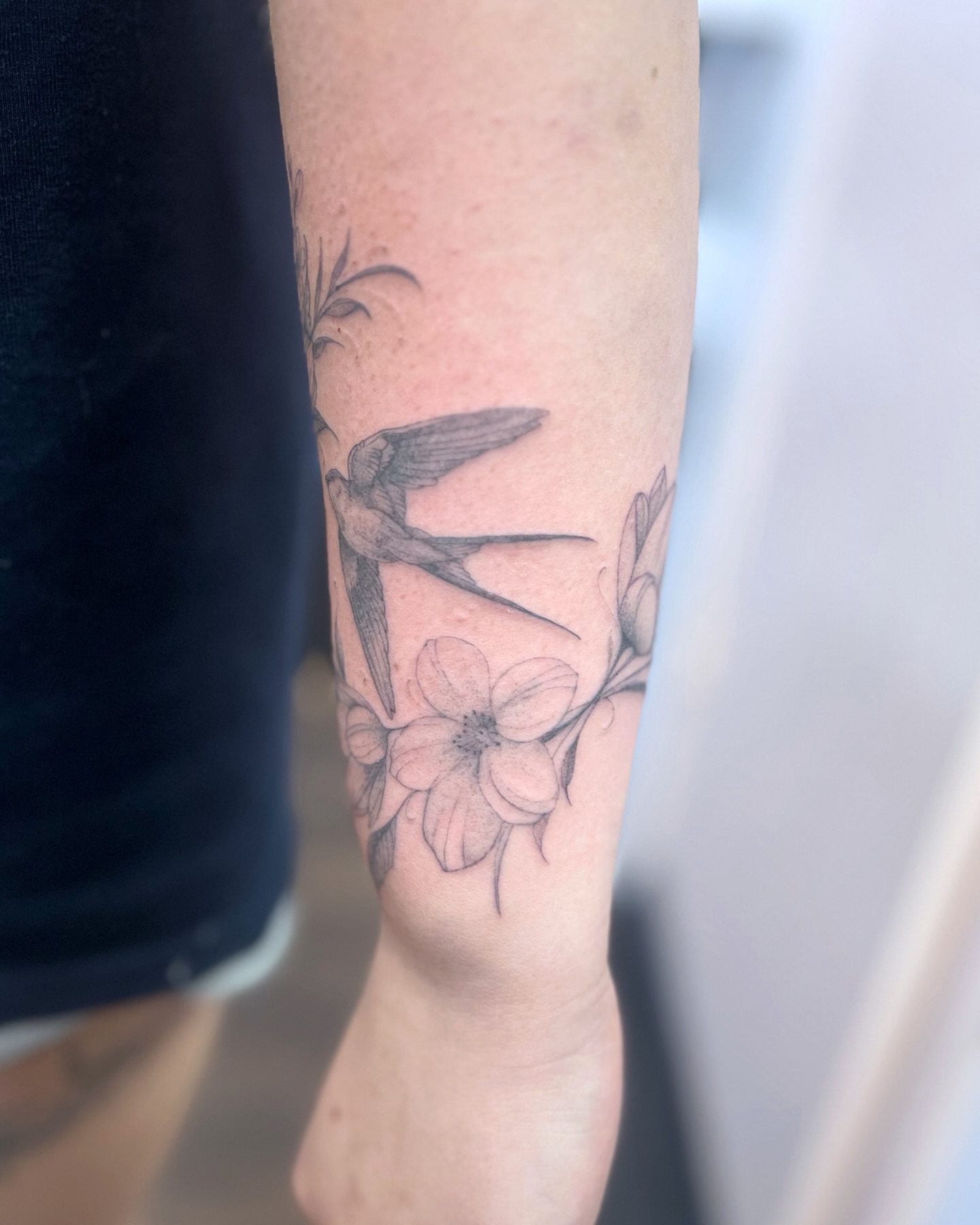 Bird and flowers black and grey tattoo on the forearm by sam cedar geller 🐝