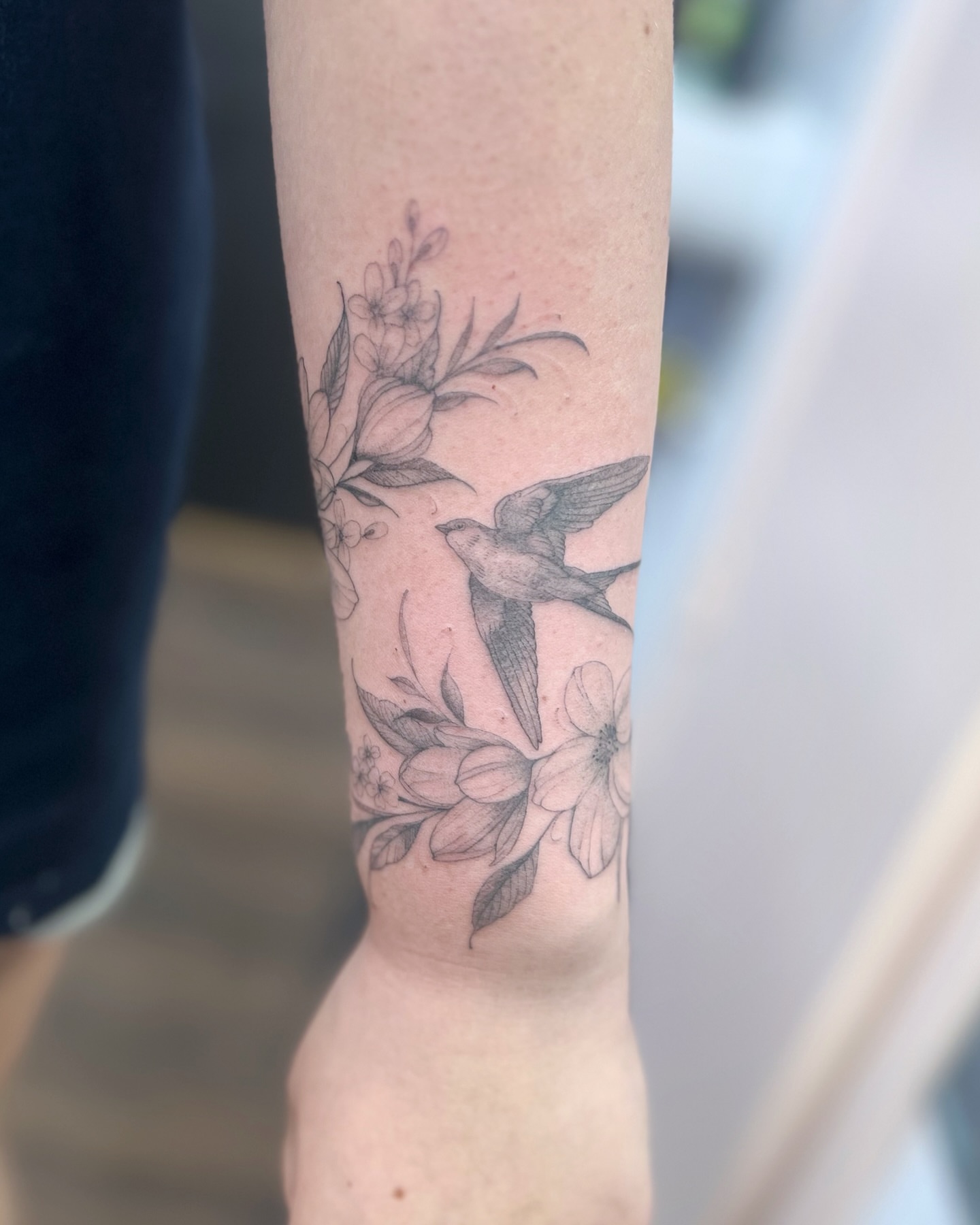Bird and flowers black and grey tattoo on the forearm by sam cedar geller 🐝