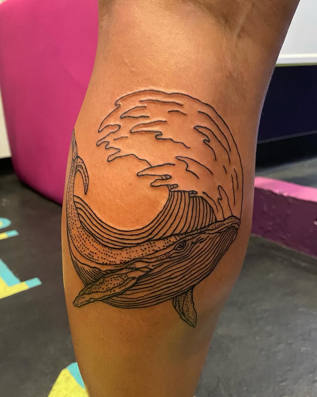 Whale and wave fine line tattoo on the thigh by Tesla Kohl