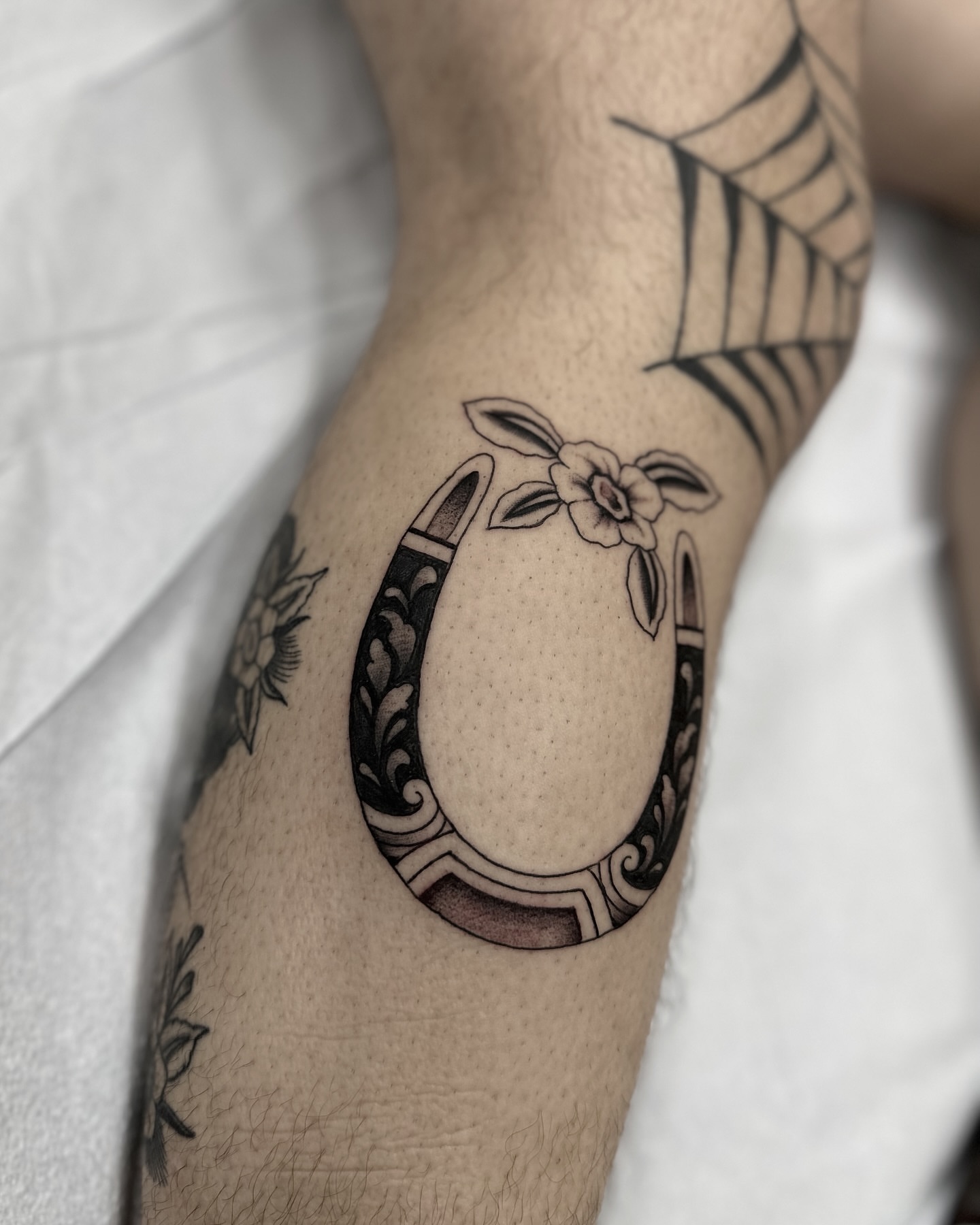 Horseshoe with flower black and grey tattoo on the forearm by Nicholas Lee, San Francisco, California