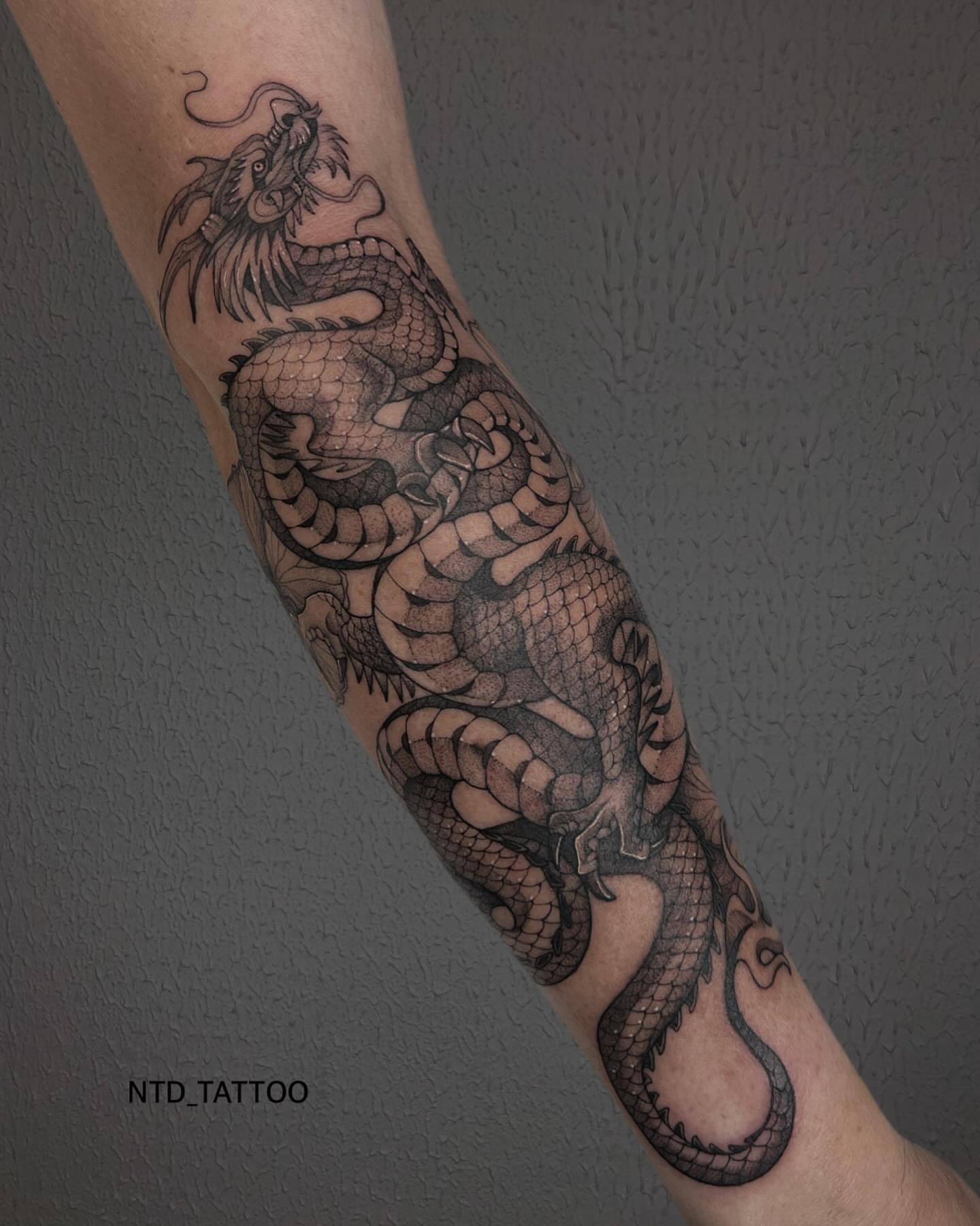 Dragon black and grey tattoo on the forearm by Tetiana Maxon