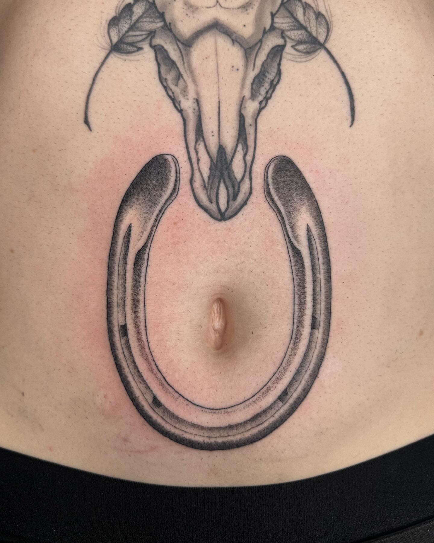 Horseshoe and skull black and grey tattoo on the torso by Finley Jordan