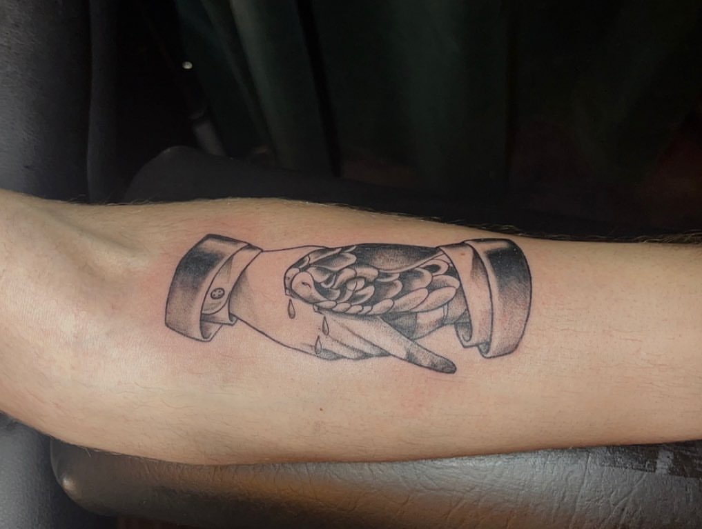 Hand holding flower black and grey tattoo on the forearm by Kenzie🖤
