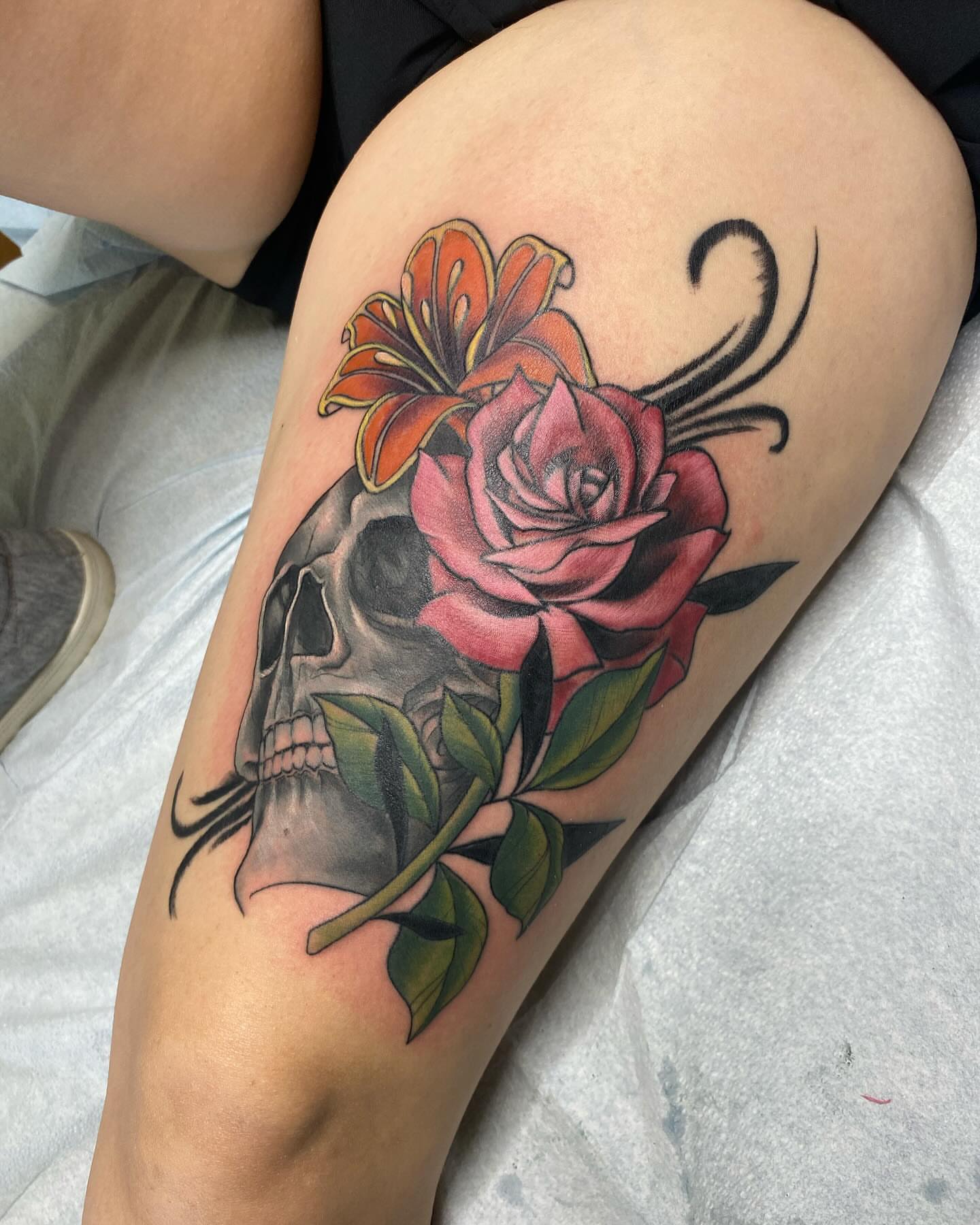 Skull and flowers American traditional tattoo on the thigh by Taya Lynn, Hudson, Wisconsin
