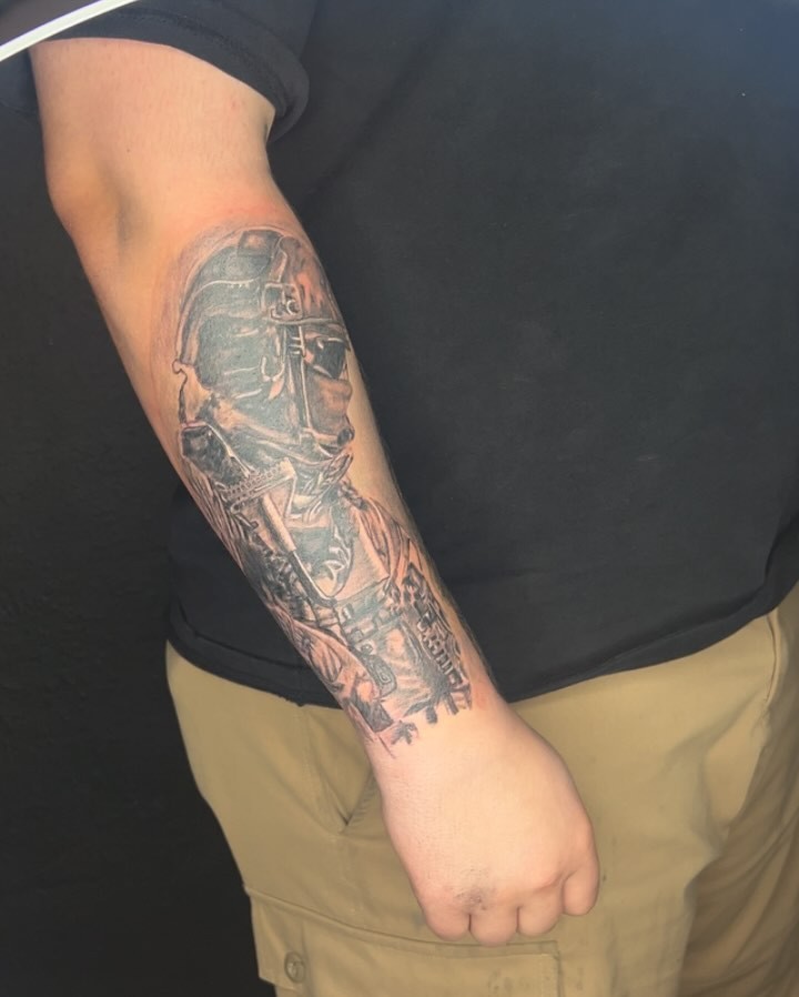 Soldier helmet black and grey tattoo on the forearm by Haley