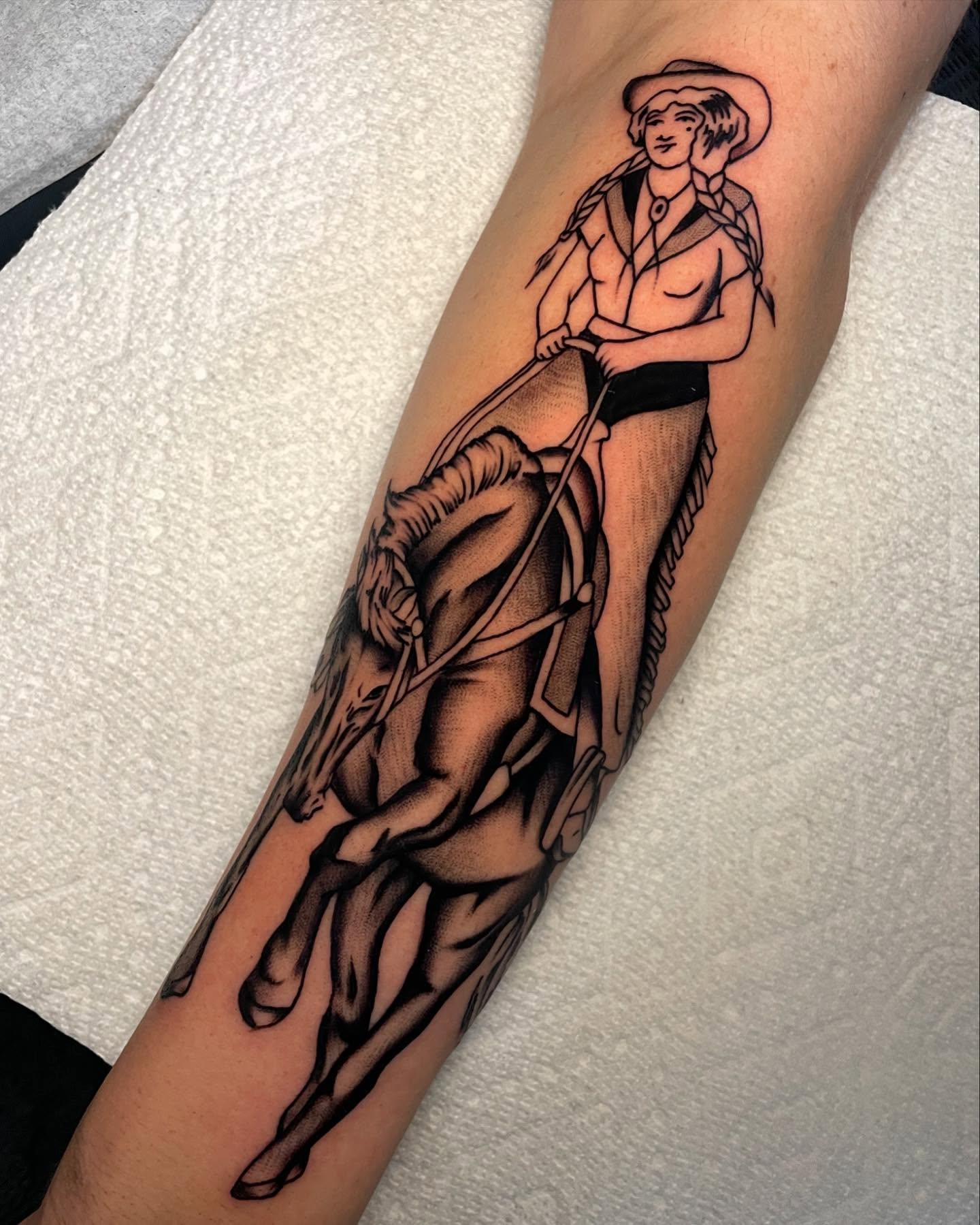 Cowgirl riding horse black and grey tattoo on the forearm by Toulouse Noble, Portland, Oregon