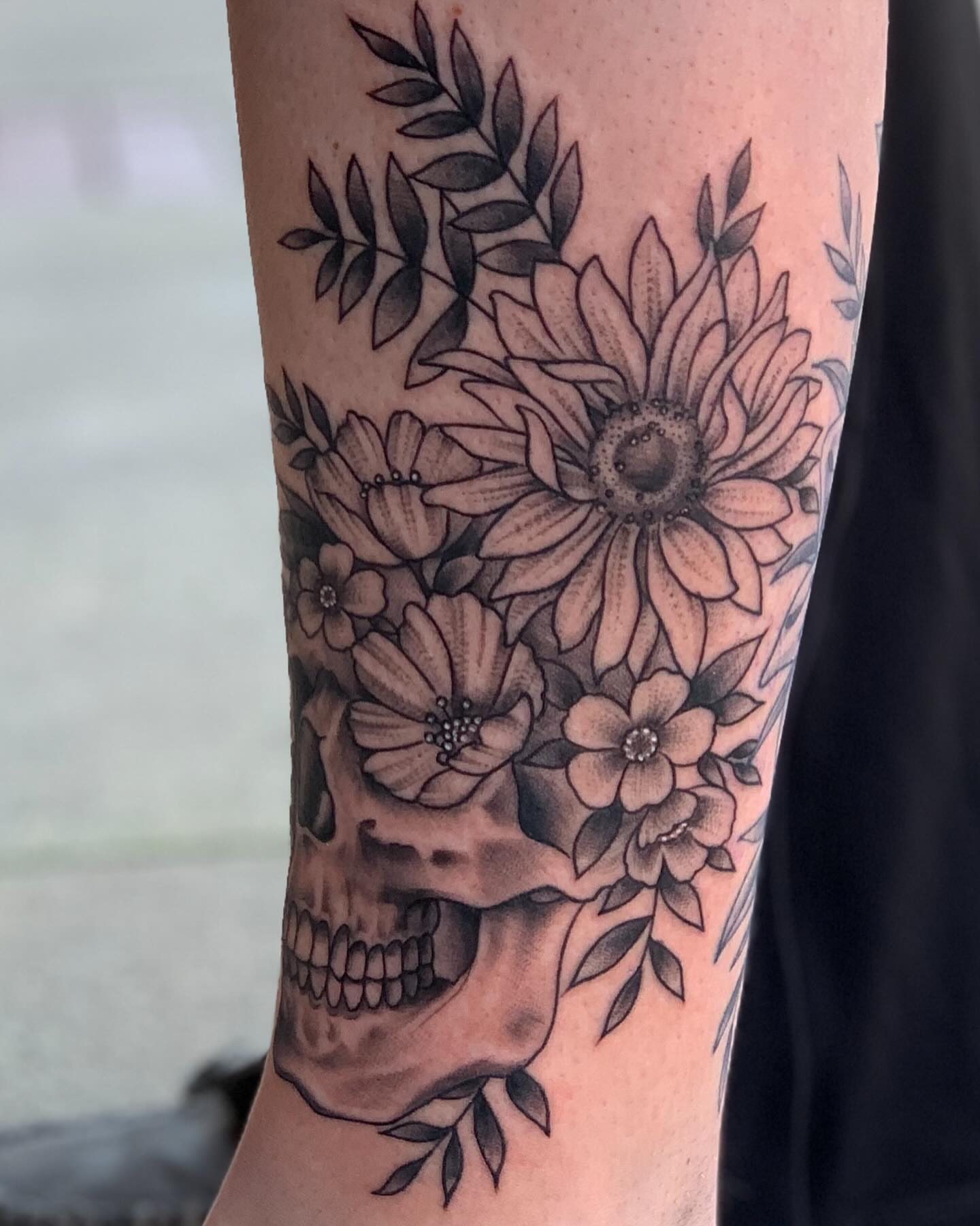 Skull and flowers dotwork tattoo on the forearm by Brad Sterling
