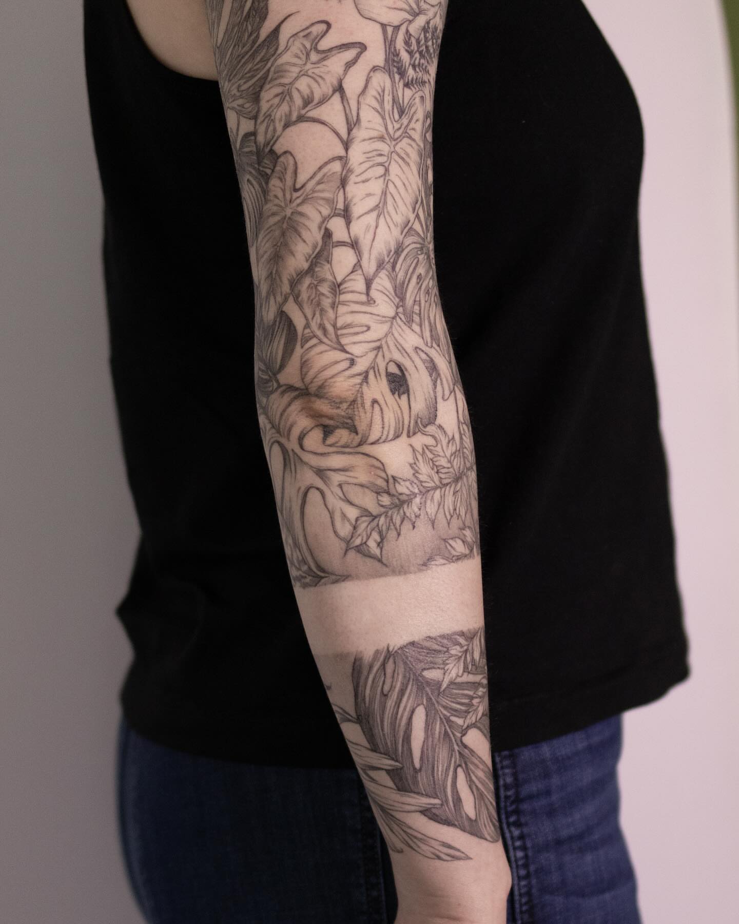 Jungle leaves and fish realism tattoo on the forearm by Seraphim