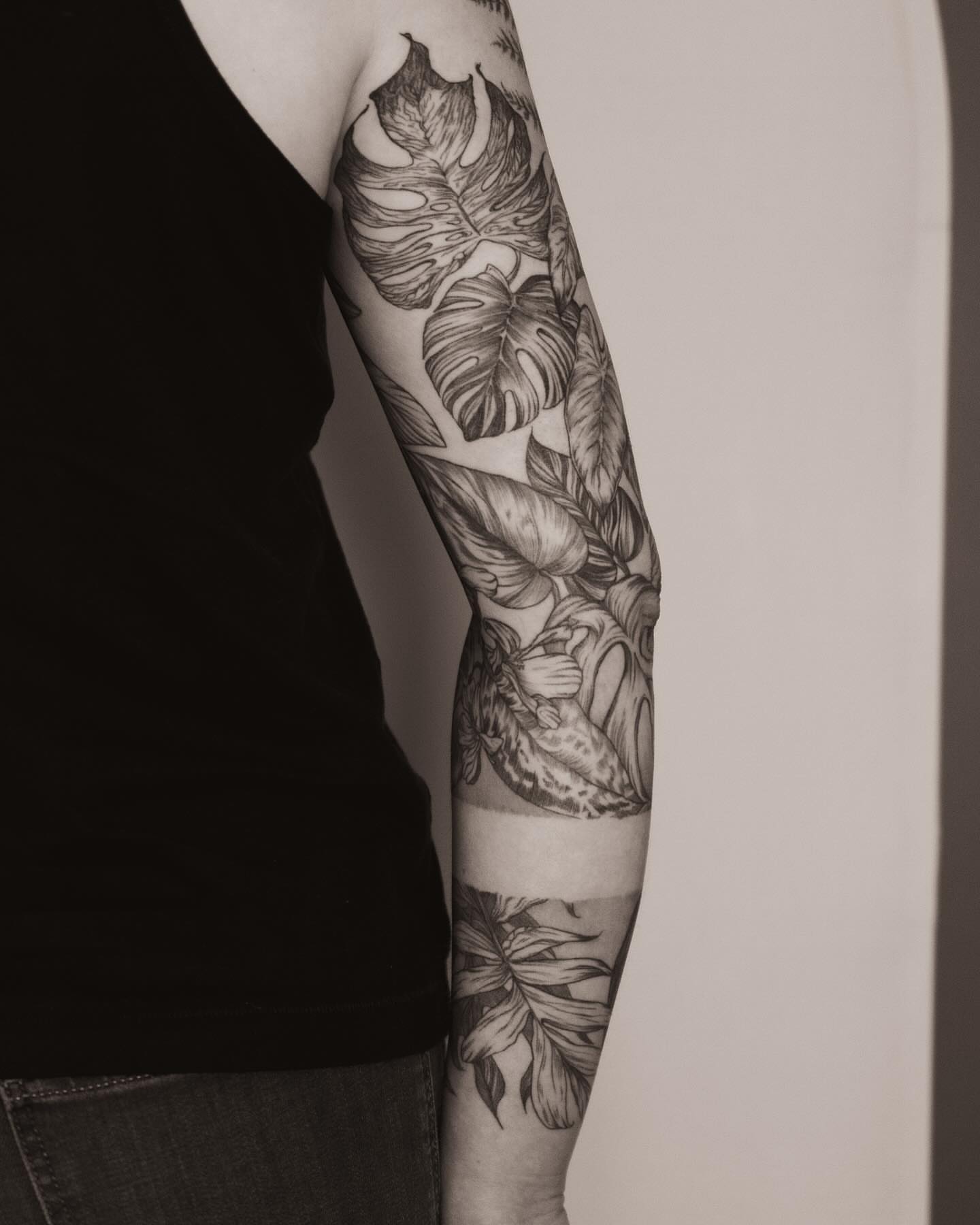Monstera leaves black and grey tattoo on the forearm by Seraphim