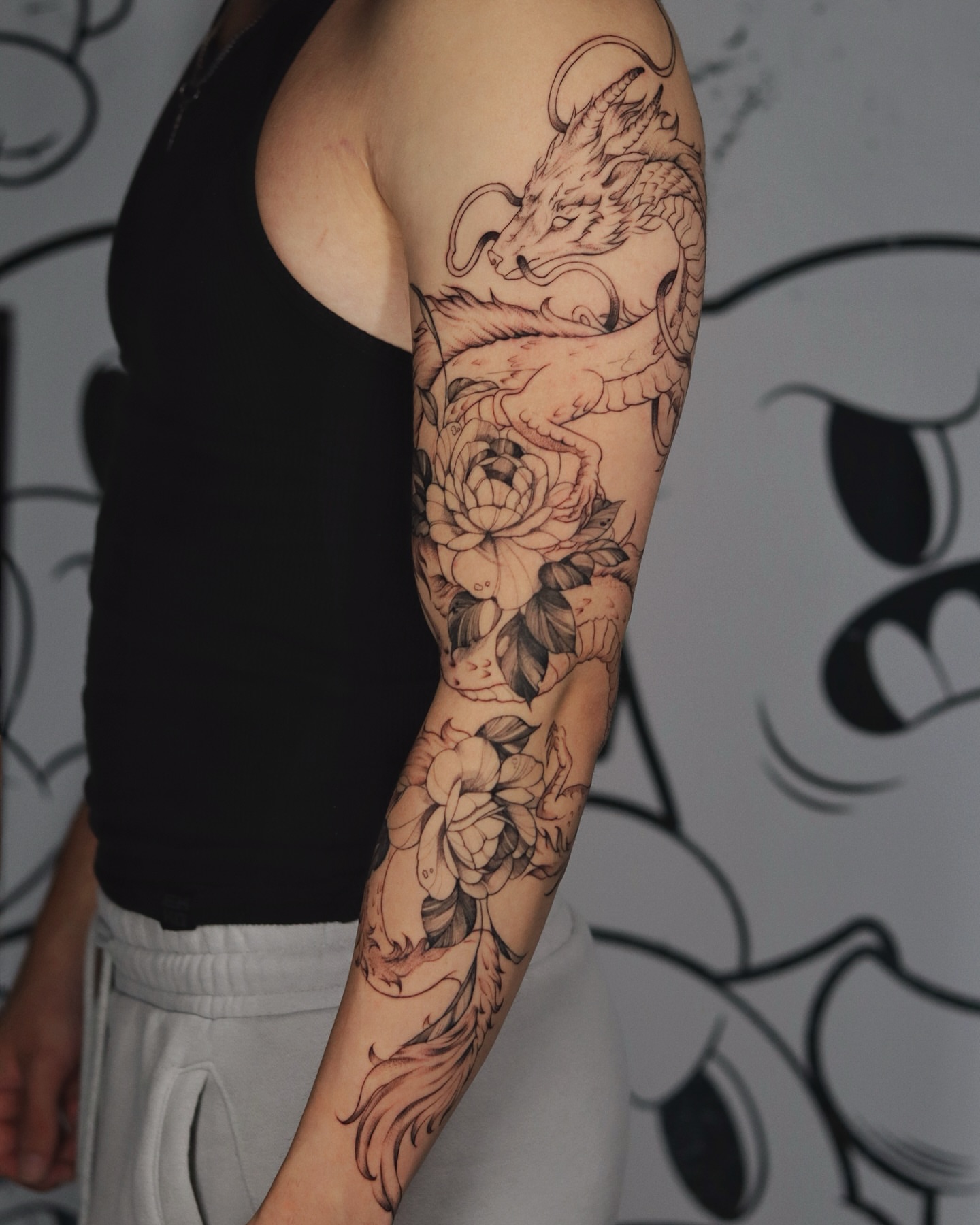 Dragon and flowers black and grey tattoo on the forearm by @katuvetattoo