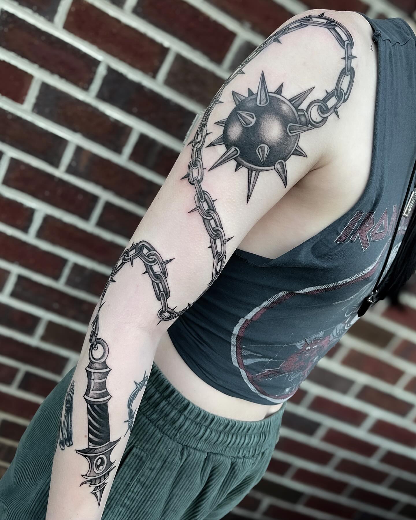 Chains and spiked ball black and grey tattoo on the forearm by Kelsi Steffensen
