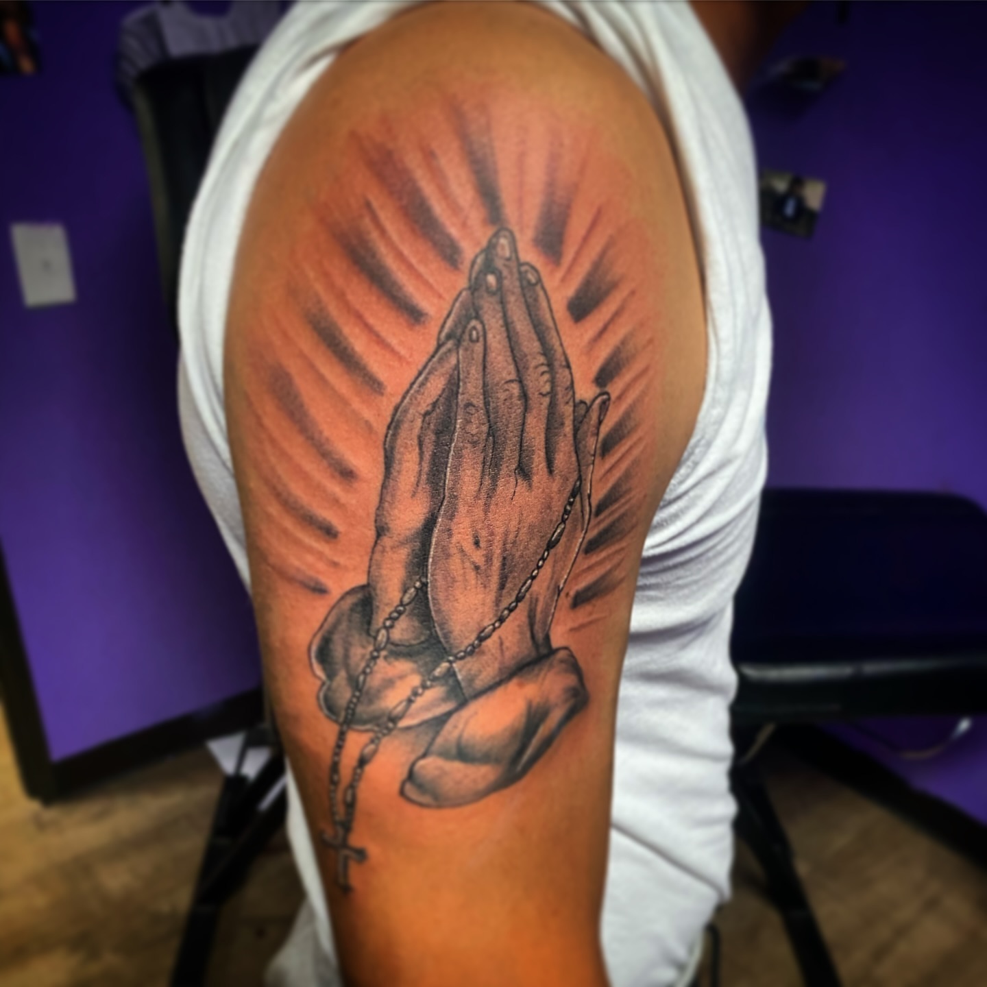 Praying hands realism tattoo on the upper arm by Rico Rosario