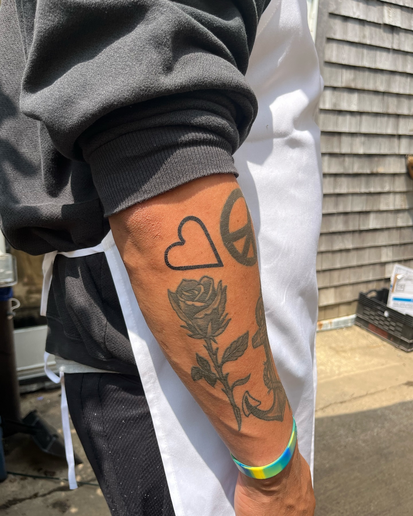 Rose and peace sign black and grey tattoo on the forearm by 잡초