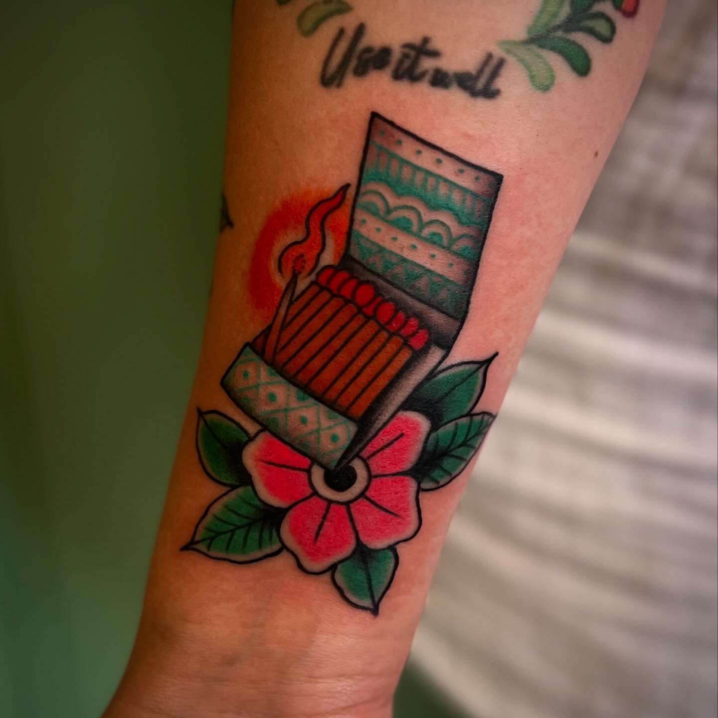 Matchbox and flower American traditional tattoo on the forearm by Chris Romolini