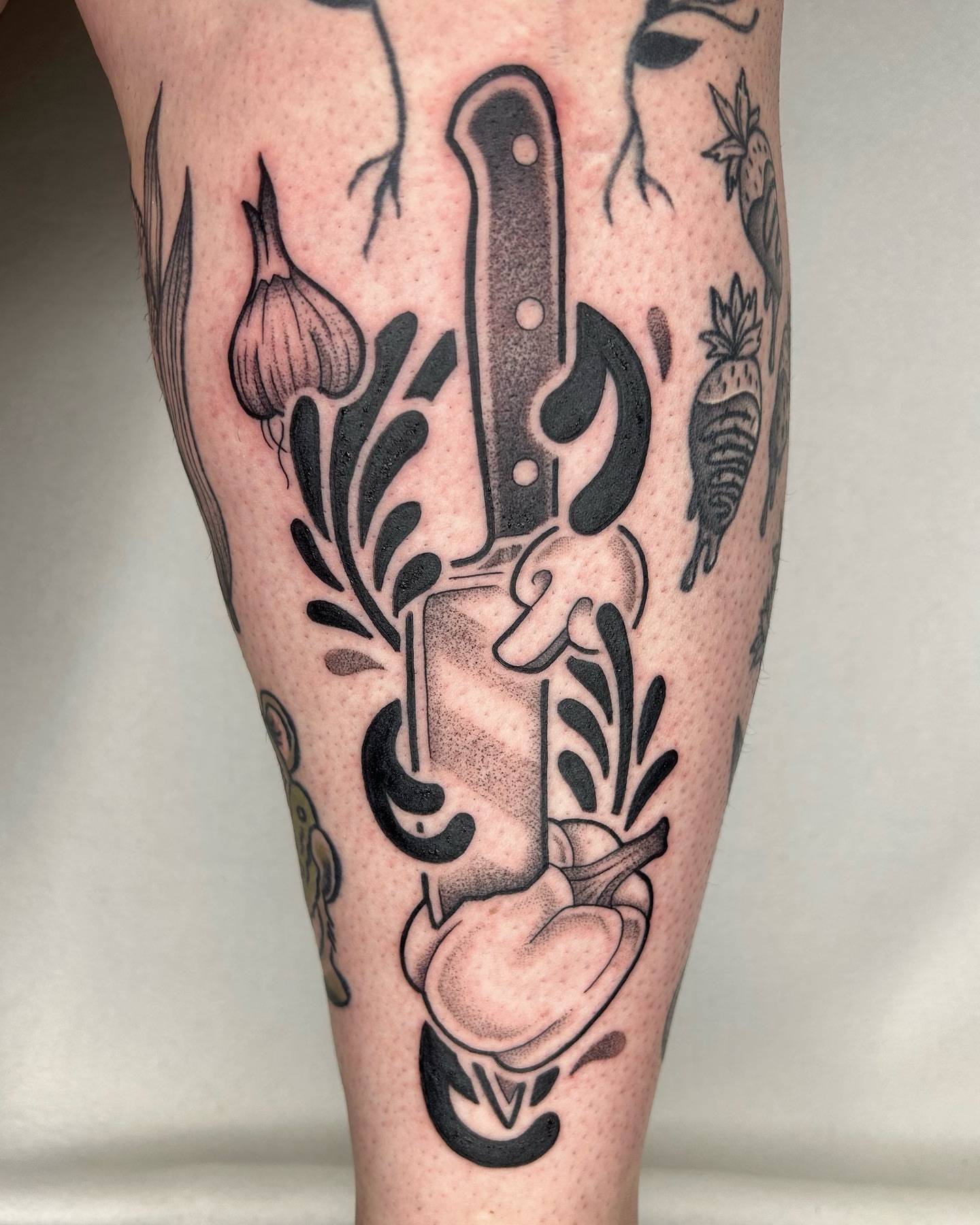 Knife and garlic black and grey tattoo on the calf by Aaron Murray ✨ Michigan Tattoo Artist