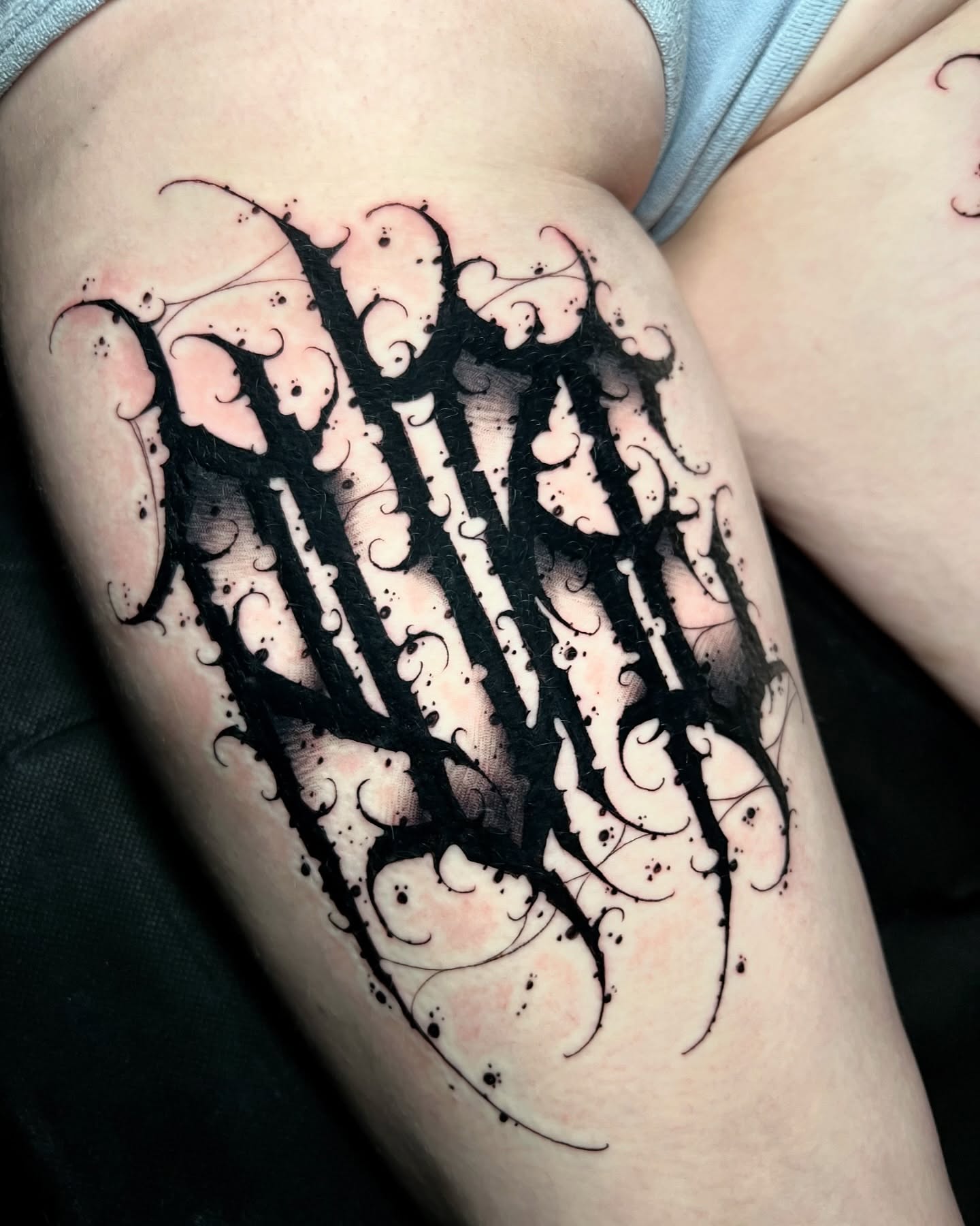 Lettering black and grey tattoo on the thigh by James Foltz