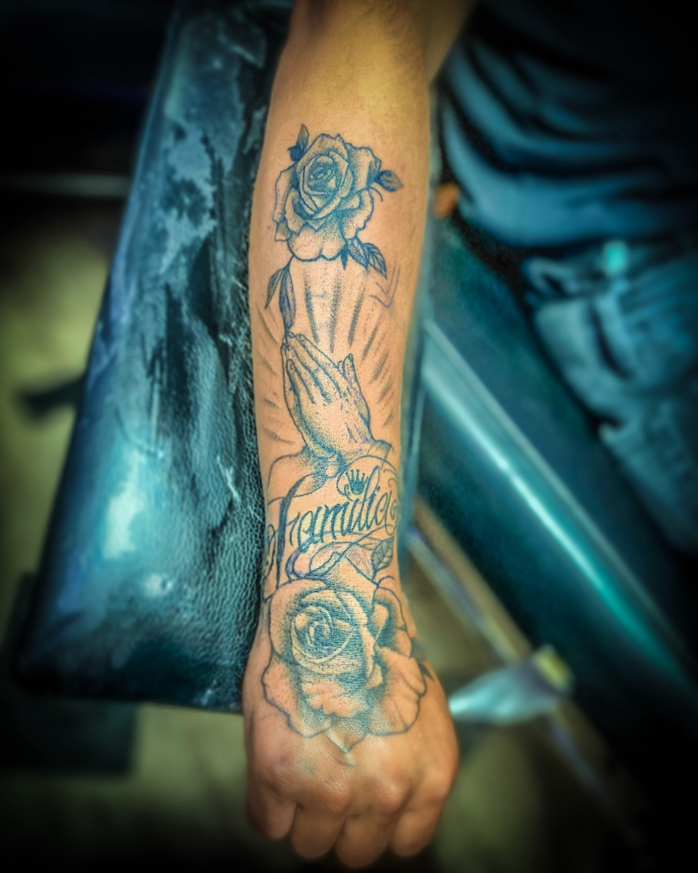 Praying hands with roses black and grey tattoo on the forearm by Rico Rosario