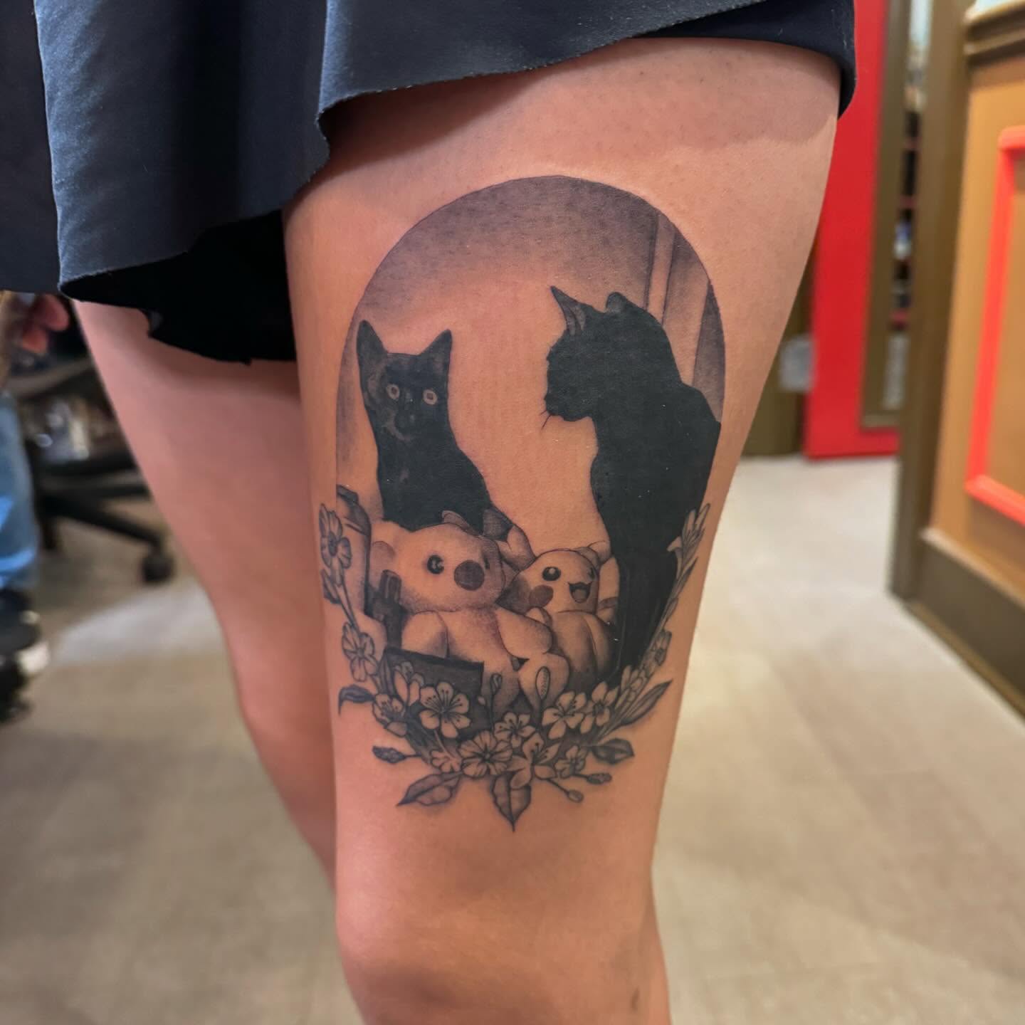 Two cats and stuffed animals black and grey tattoo on the thigh by 🦇💀Matt Perlman💀🦇