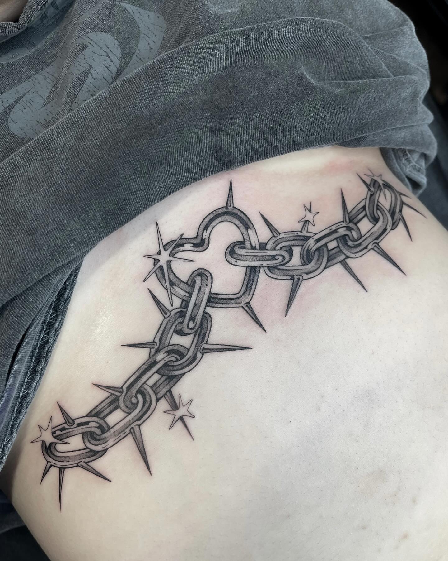 Barbed wire and chain black and grey tattoo on the ribs by Kelsi Steffensen