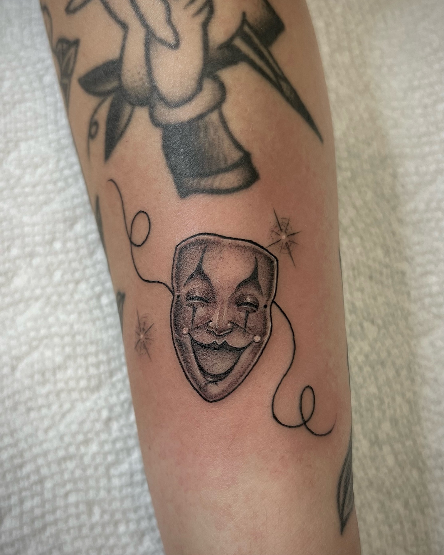 Clown mask black and grey tattoo on the forearm by Valerie Dominguez