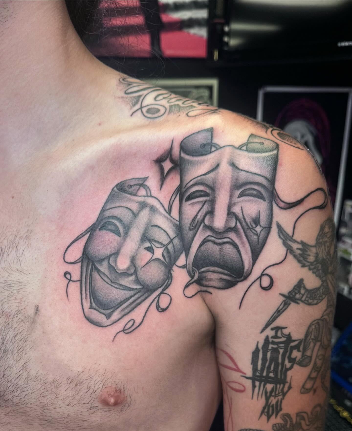 Theater masks black and grey tattoo on the shoulder by Colby McClain