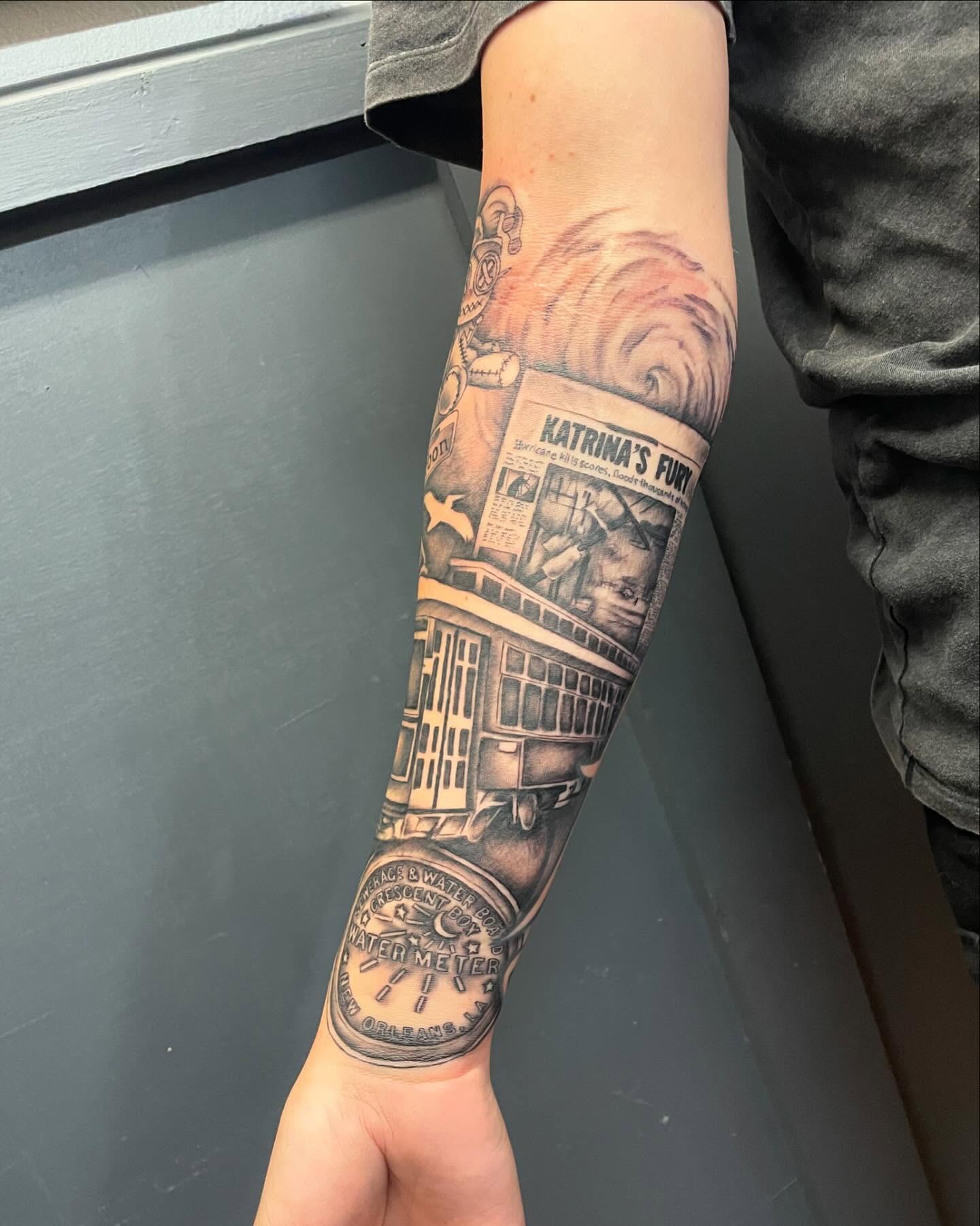 Streetcar and newspaper black and grey tattoo on the forearm by Blake