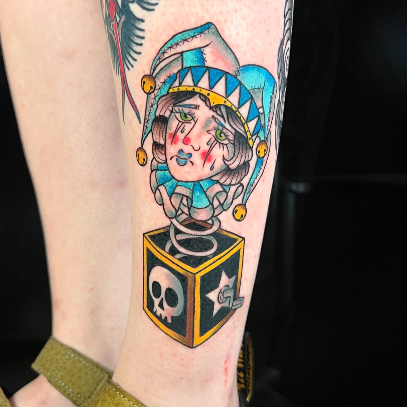 Jester head in jack-in-the-box American traditional tattoo on the forearm by Tattoo & Body Artist, Gastonia, North Carolina