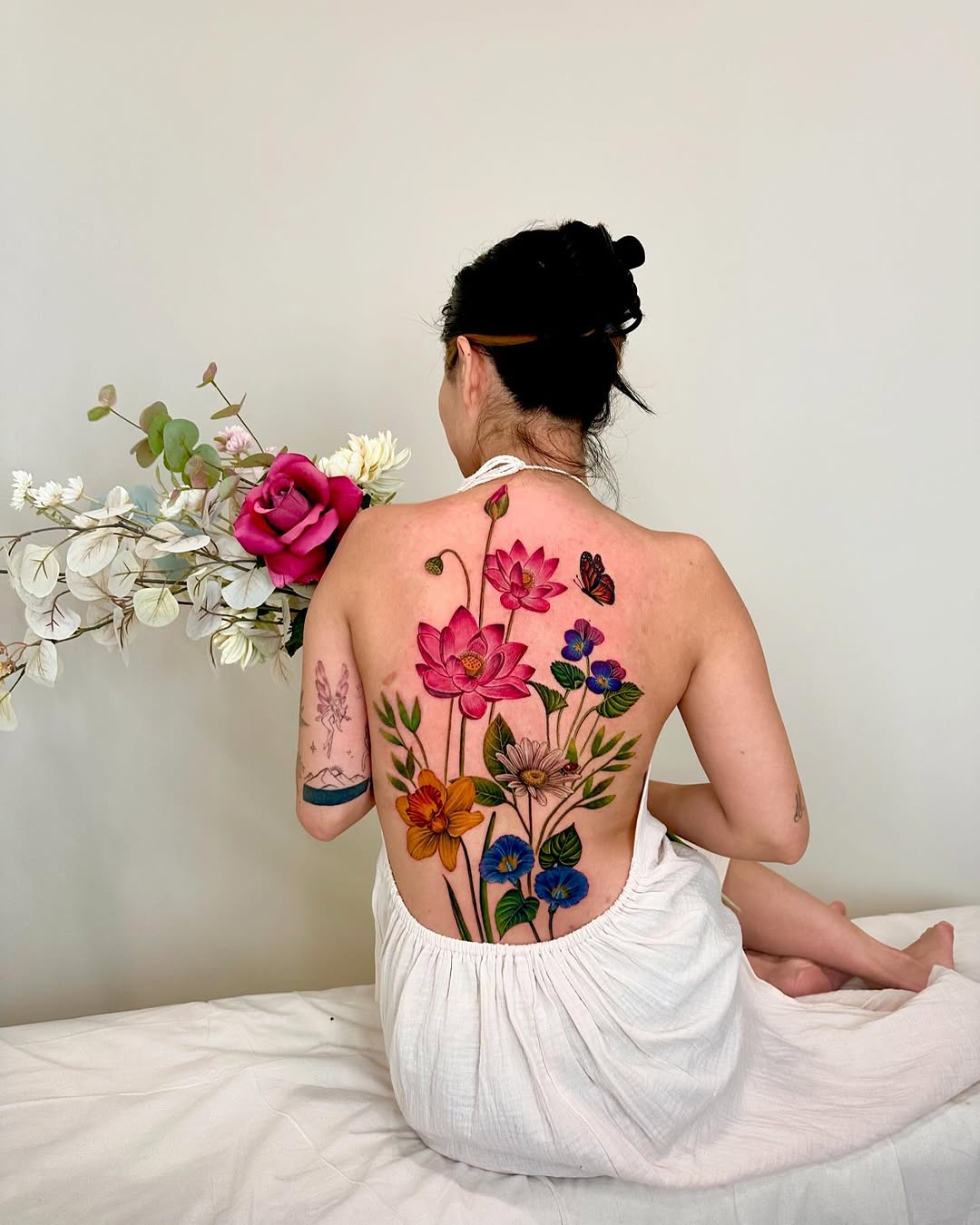 Full back floral arrangement with butterflies watercolor tattoo on the back by Claire