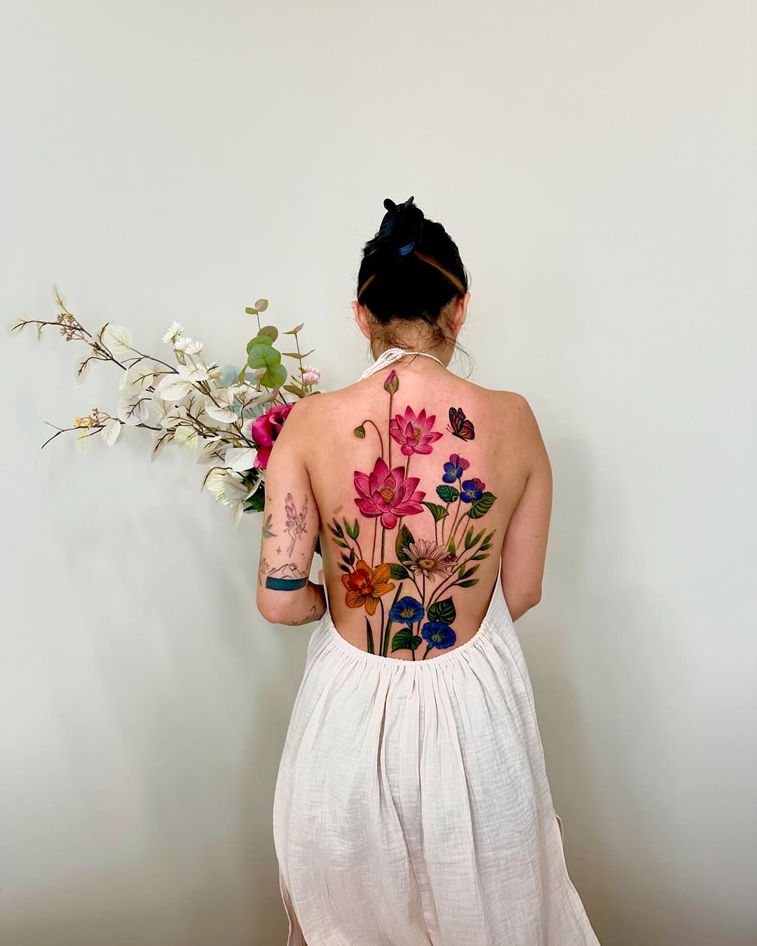 Floral arrangement with butterflies watercolor tattoo on the back by Claire