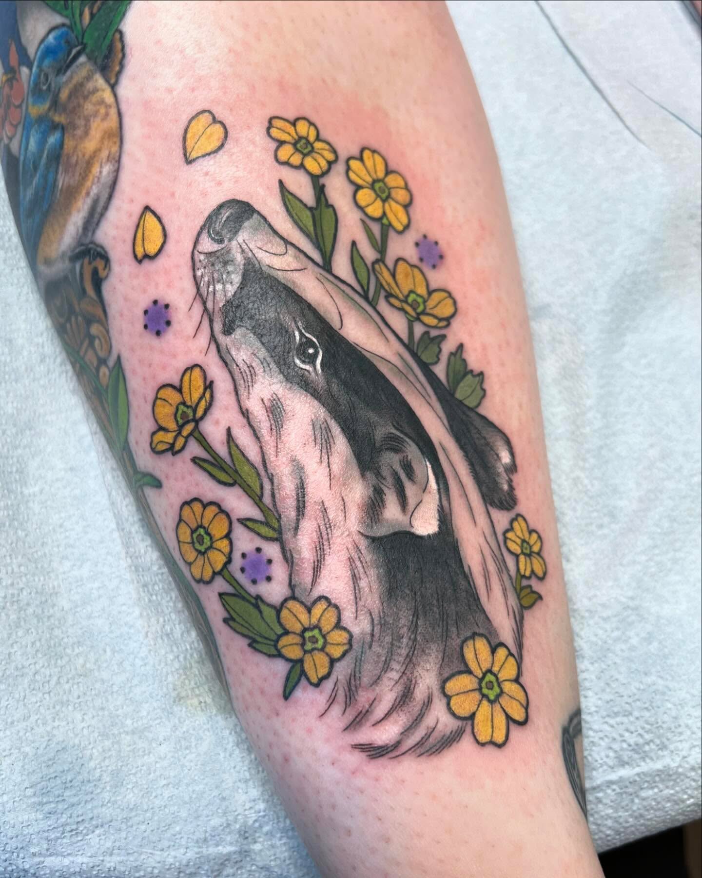 Dog and flowers realism tattoo on the forearm by Caitlin Stairs