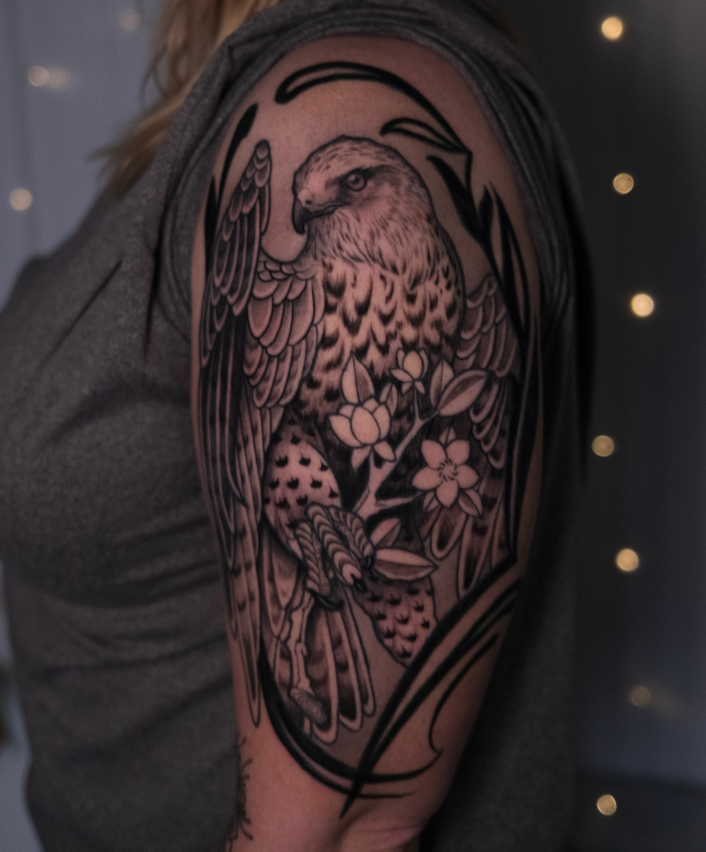 Hawk and flowers black and grey tattoo on the shoulder by Lorenzo Lopez