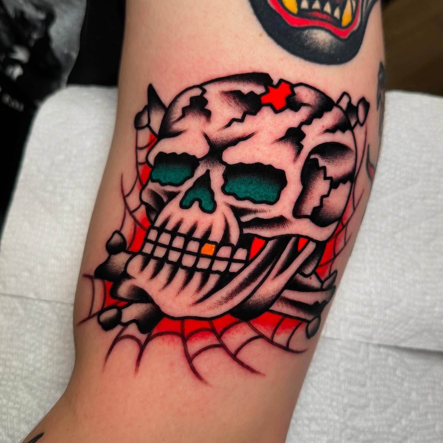 Grinning skull American traditional tattoo on the forearm by John Lemon