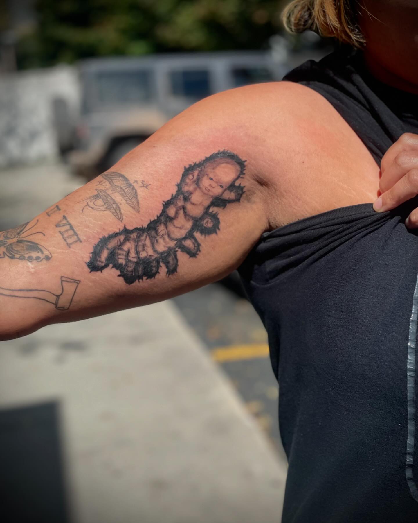 Baby caterpillar black and grey tattoo on the upper arm by Kaylee 🗡️
