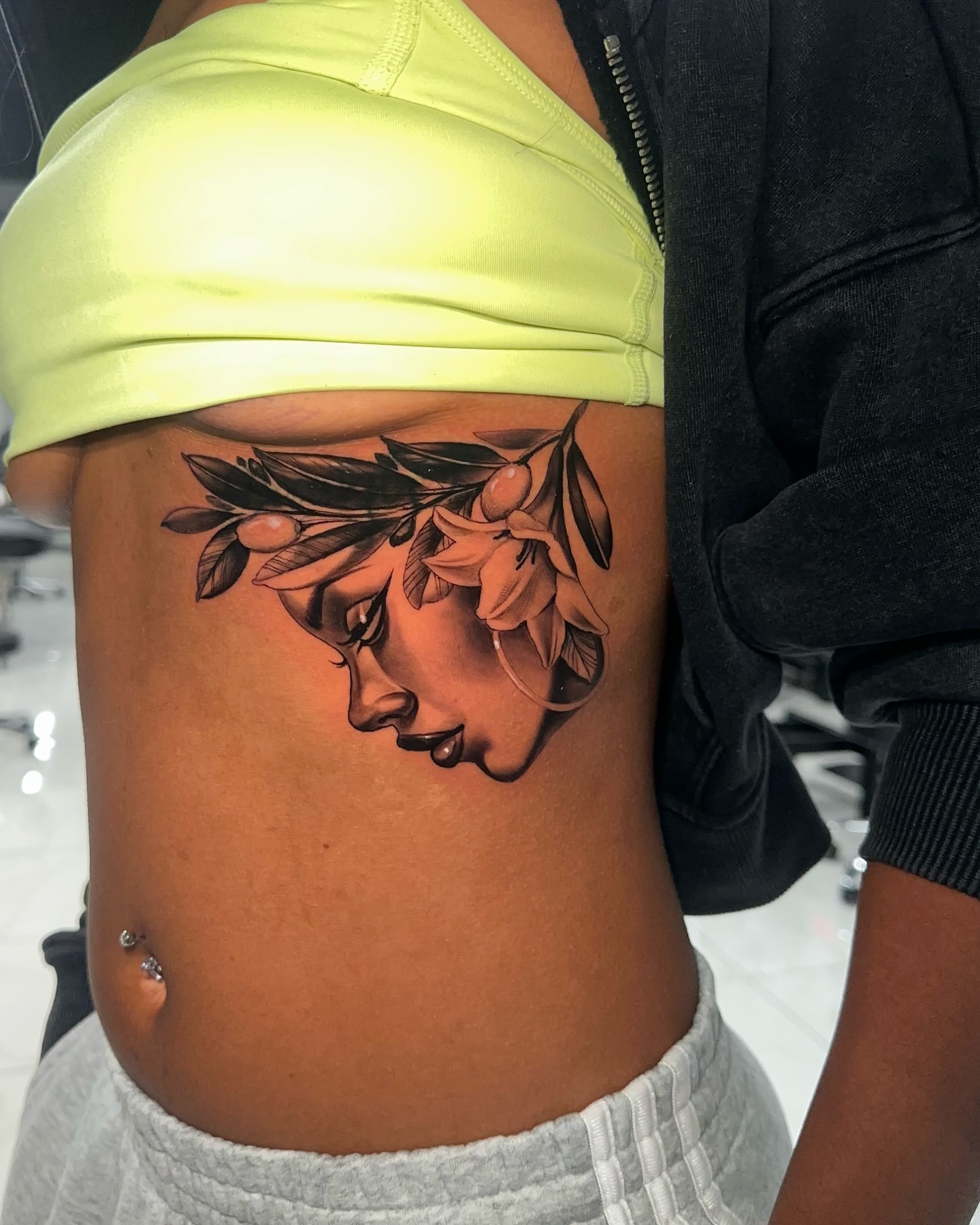 Woman's face with olive branch realism tattoo on the ribs by Joey Hella Tattoo Artist