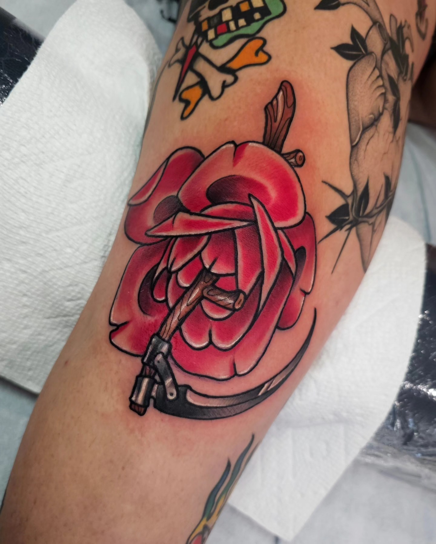 Red rose with gun American traditional tattoo on the forearm by Shannon
