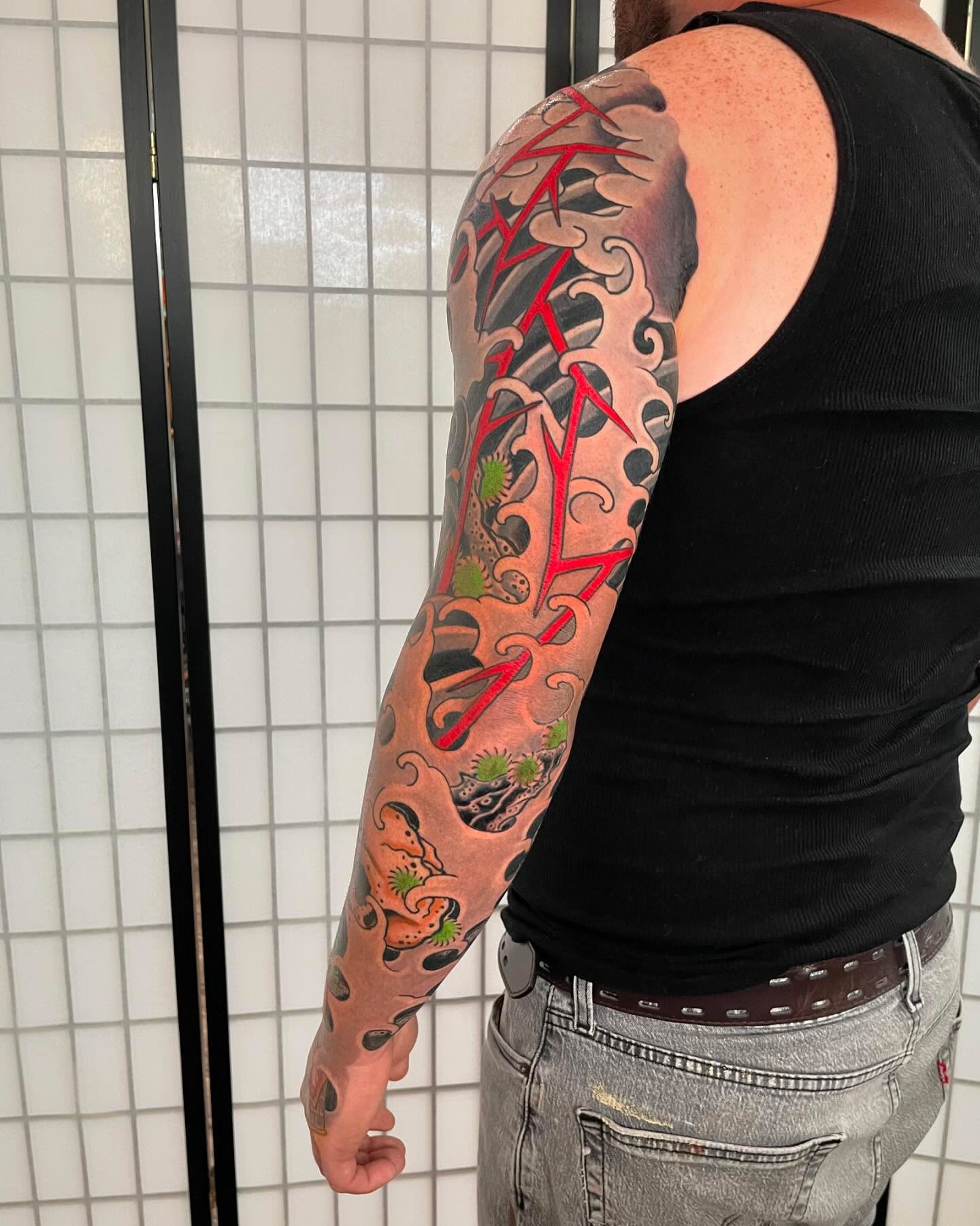 Wave and koi japanese irezumi tattoo on the upper arm by Caleb Baker