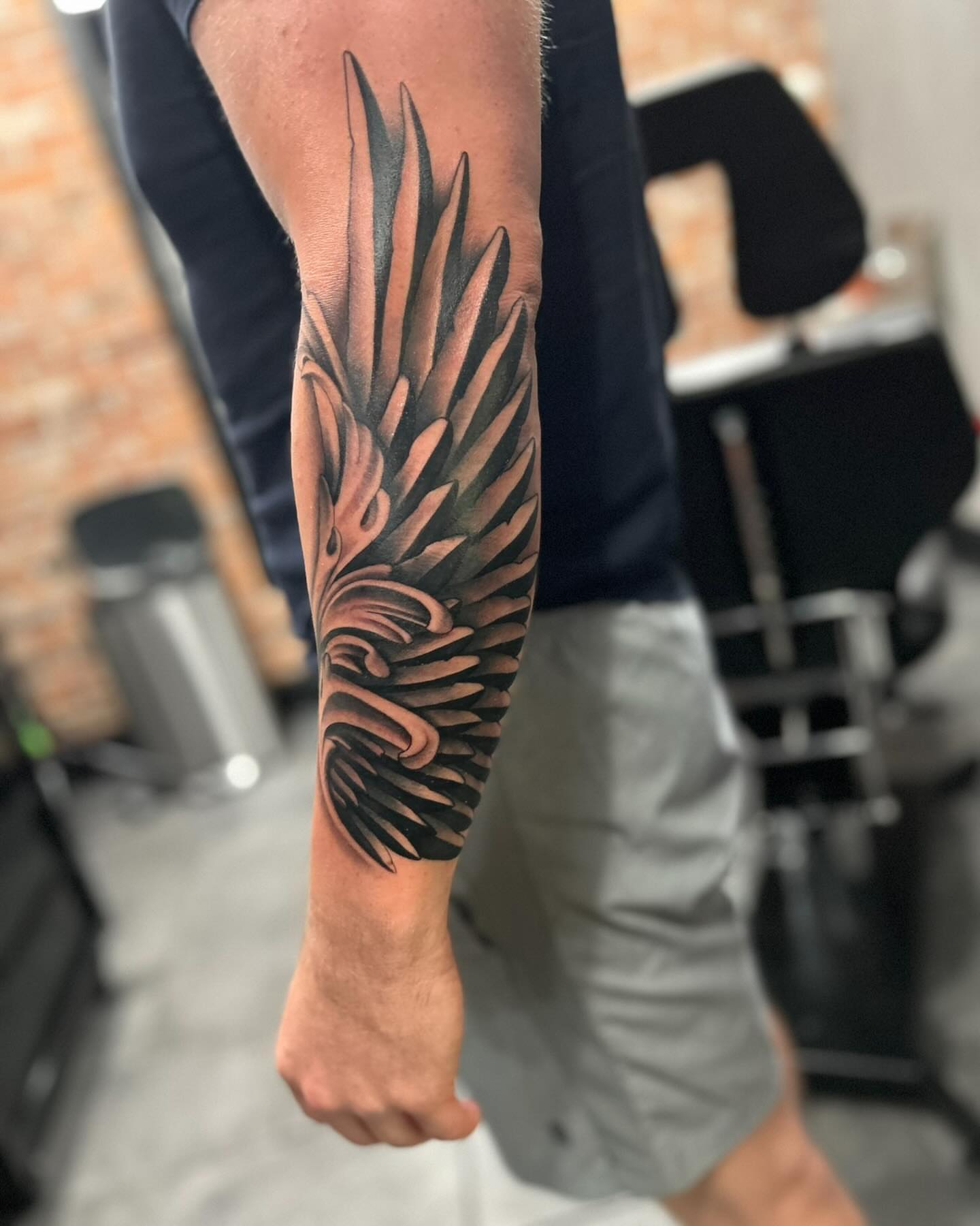 Wing black and grey tattoo on the forearm by Brian Keith