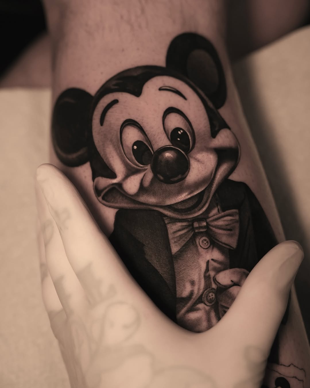Mickey Mouse in a tuxedo new school tattoo on the forearm by @kotytattoos