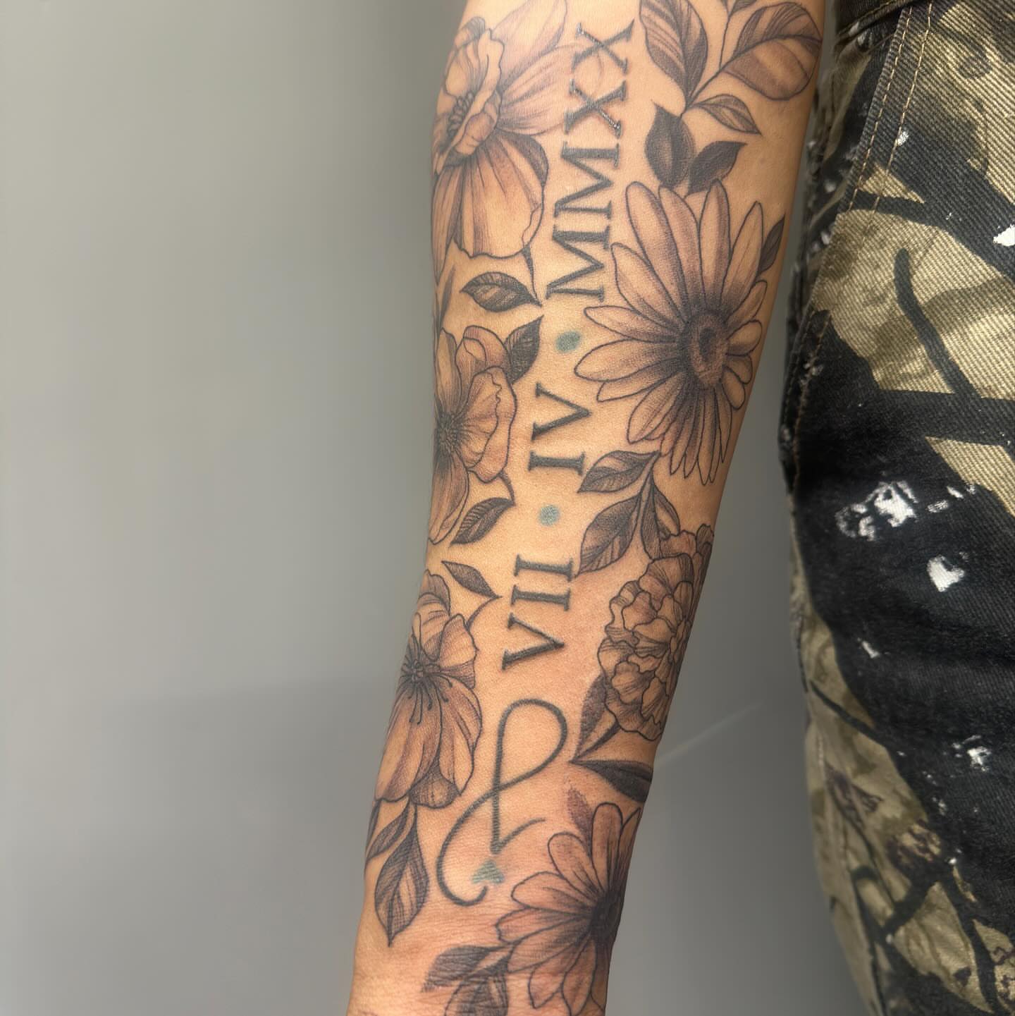 Floral arrangement with Roman numerals black and grey tattoo on the forearm by Detroit Tattoo Artist