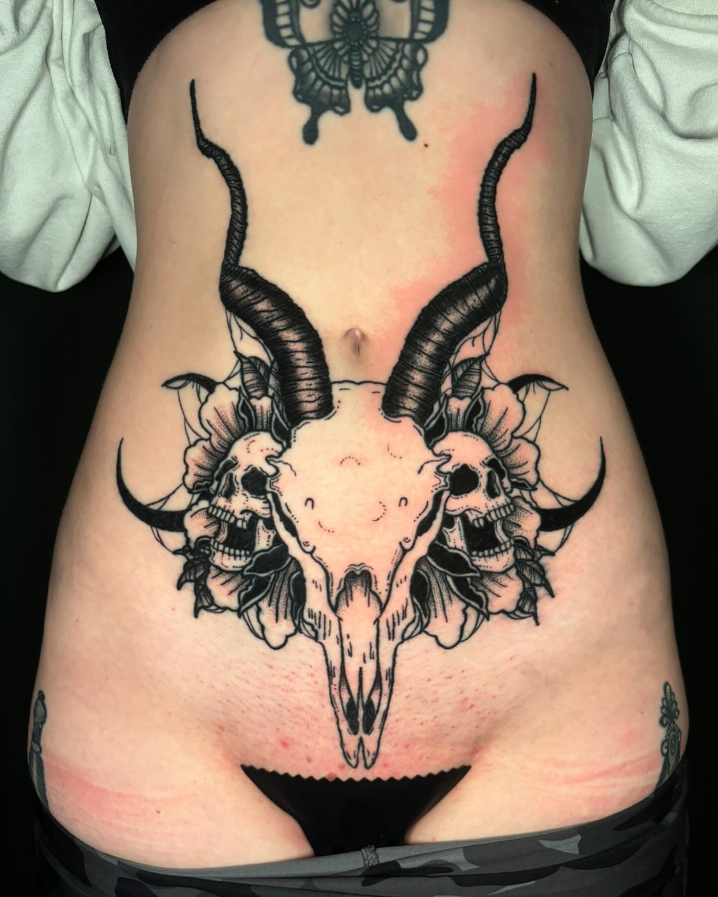 Bull skull with skulls black and grey tattoo on the torso by Bryan Black