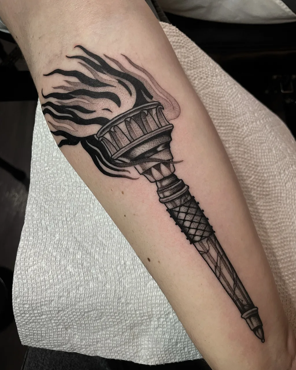 Statue of liberty torch black and grey tattoo on the forearm by Lauren Vandevier